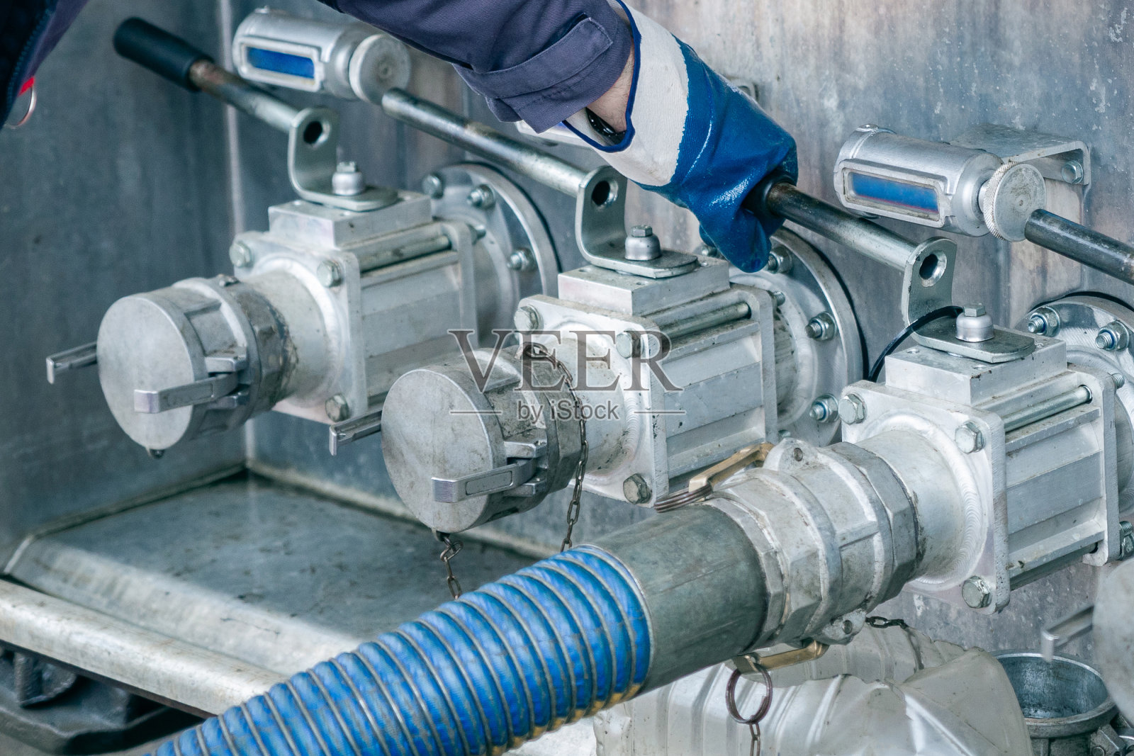 工人在加油站把油排到油箱里。照片摄影图片