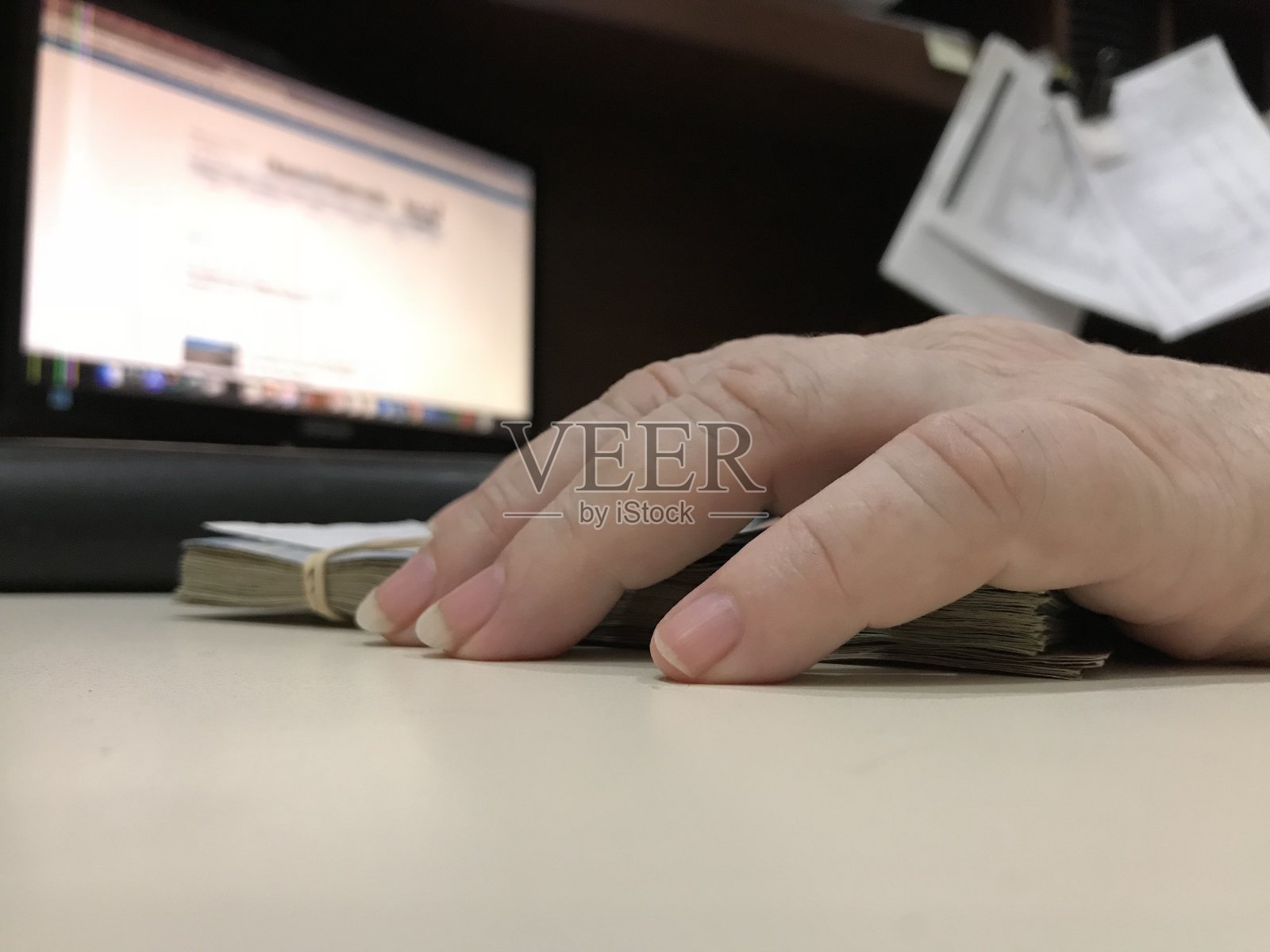 米色的桌子上放着许多混合的墨西哥比索钞票,一只手摸着它们照片摄影图片