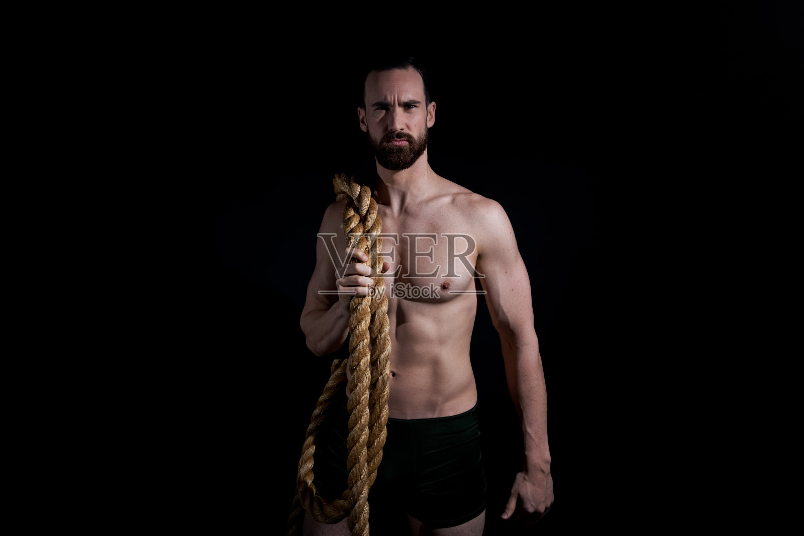 性感的赤膊男人在内衣和抱着绳子照片摄影图片