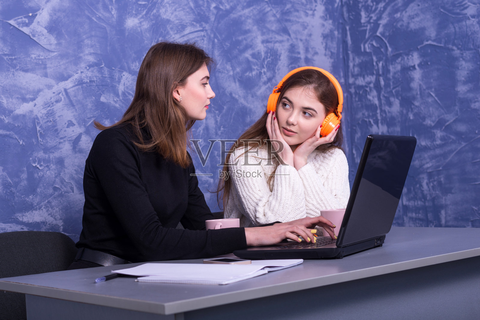 两个女商人正在一台笔记本电脑后面讨论一个商业项目照片摄影图片