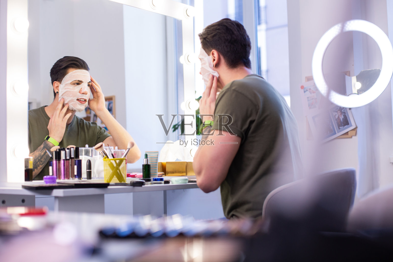 好奇的纹身男子坐在工作室里测试新面具照片摄影图片