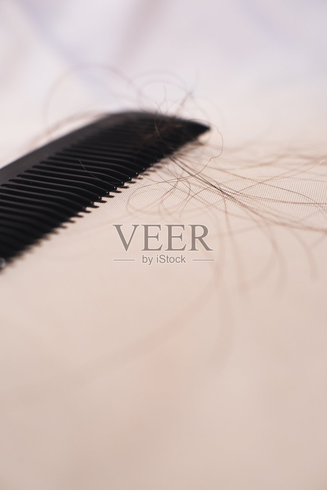 特写的黑色梳子与棕色的头发在明亮的织物。照片摄影图片