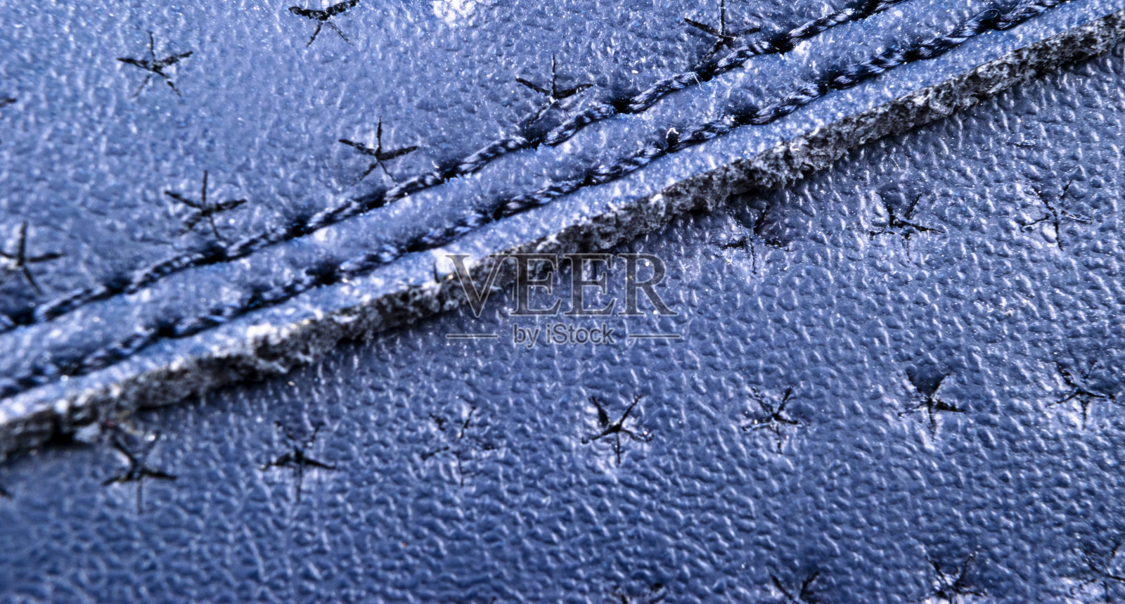 蓝色穿孔皮革纹理背景。蓝色皮革,缝合紧密。微距镜头闪光的皮革纹理。照片摄影图片