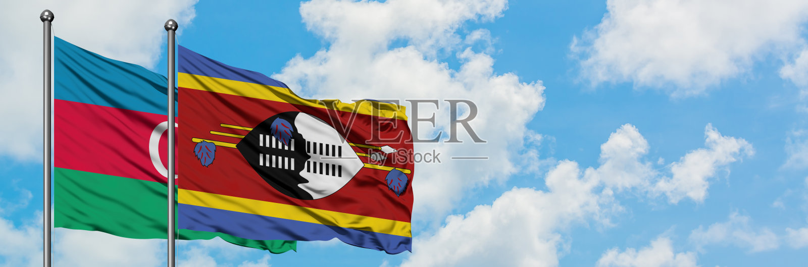 阿塞拜疆和斯威士兰的国旗在风中飘扬,对抗着白色多云的蓝天。外交理念,国际关系。照片摄影图片