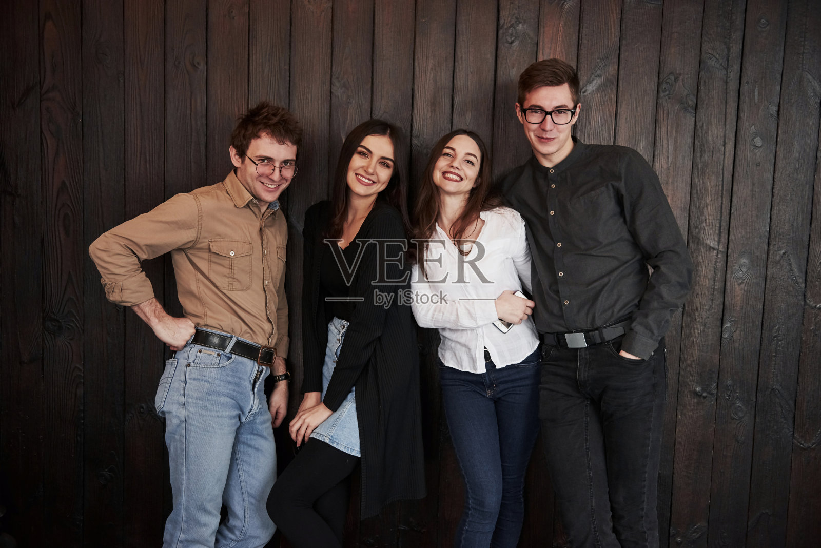 在餐厅。青年靠着黑色的木墙站着。一群朋友聚在一起照片摄影图片