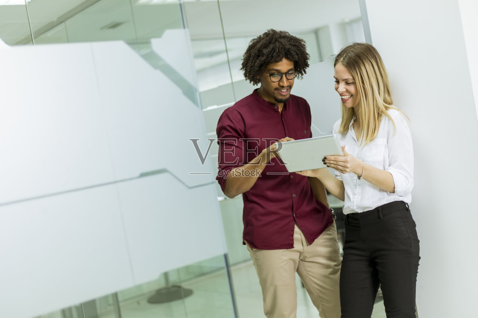 非裔美国商人和白人女商人用平板电脑站在办公室里照片摄影图片