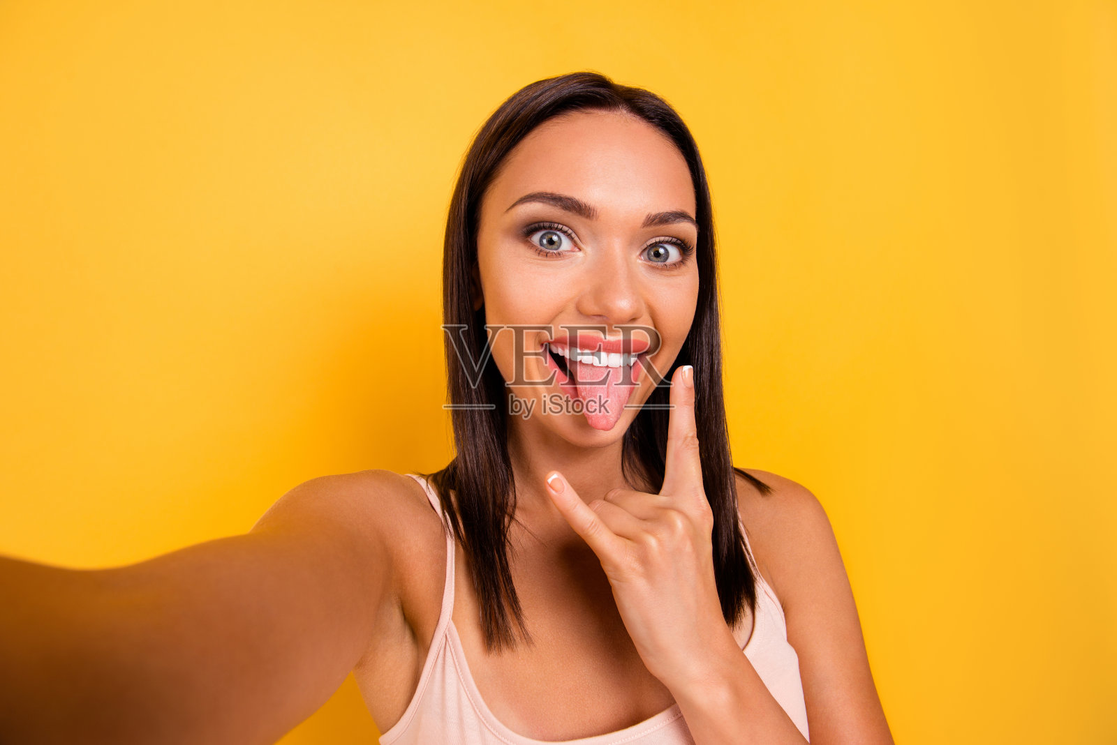 近距离的照片美丽惊人的她她的夫人使自拍instagram粉丝硬摇滚喇叭象征舌头伸出嘴穿着休闲柔和的背心孤立的黄色明亮的背景照片摄影图片