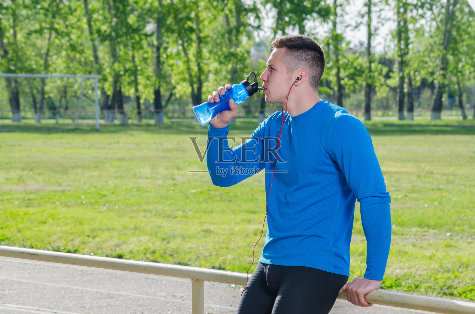 一个戴着耳机喝水的年轻运动员的肖像照片摄影图片