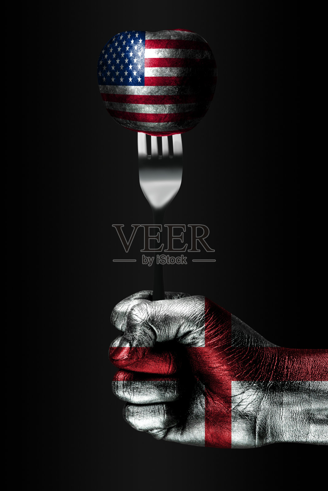 一只画着英国国旗的手握着一个叉子,叉子上是一个画着美国国旗的球,这是一种影响、压力、紧握和无趣的标志。照片摄影图片