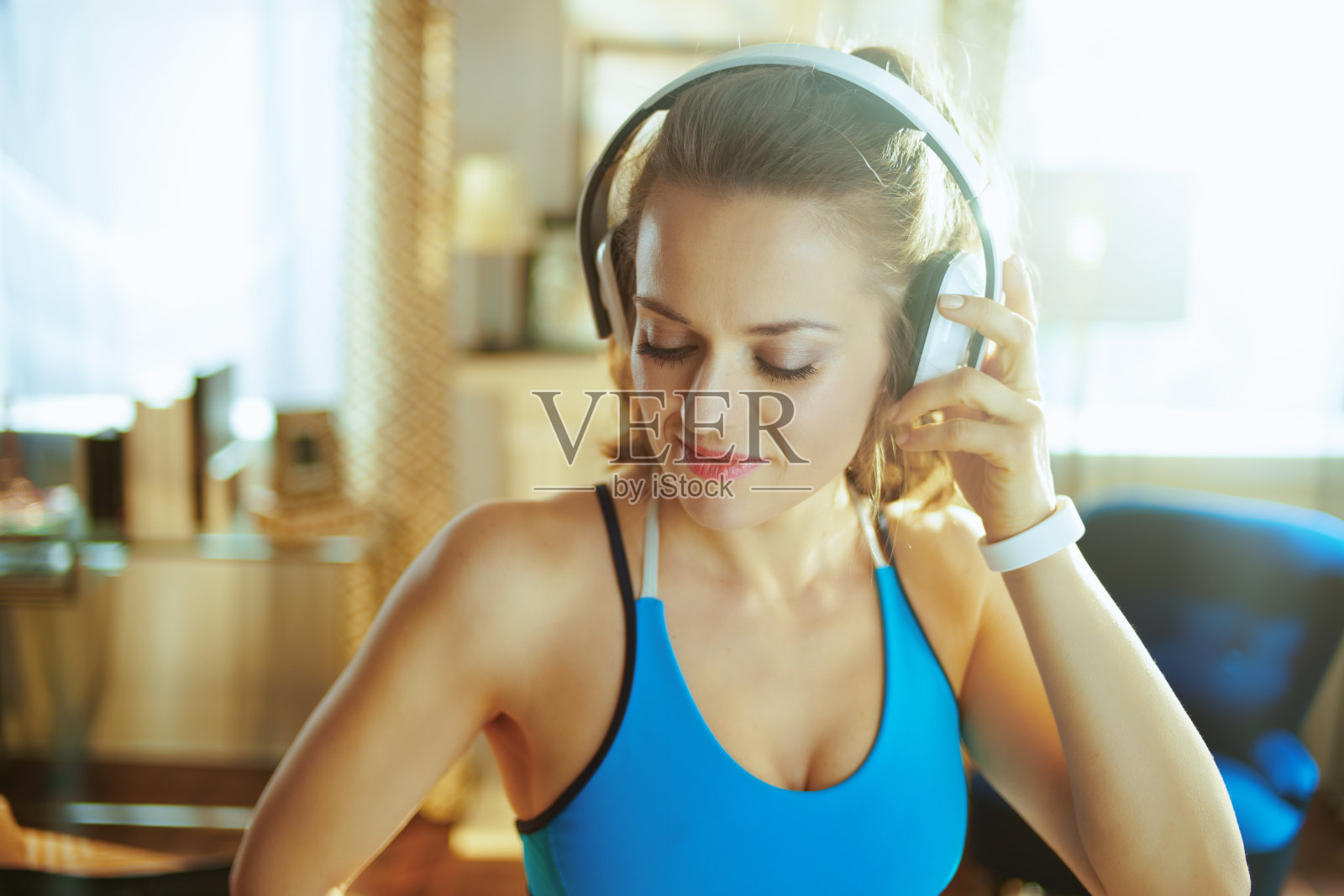 年轻女子在现代的房子里戴着耳机听音乐照片摄影图片