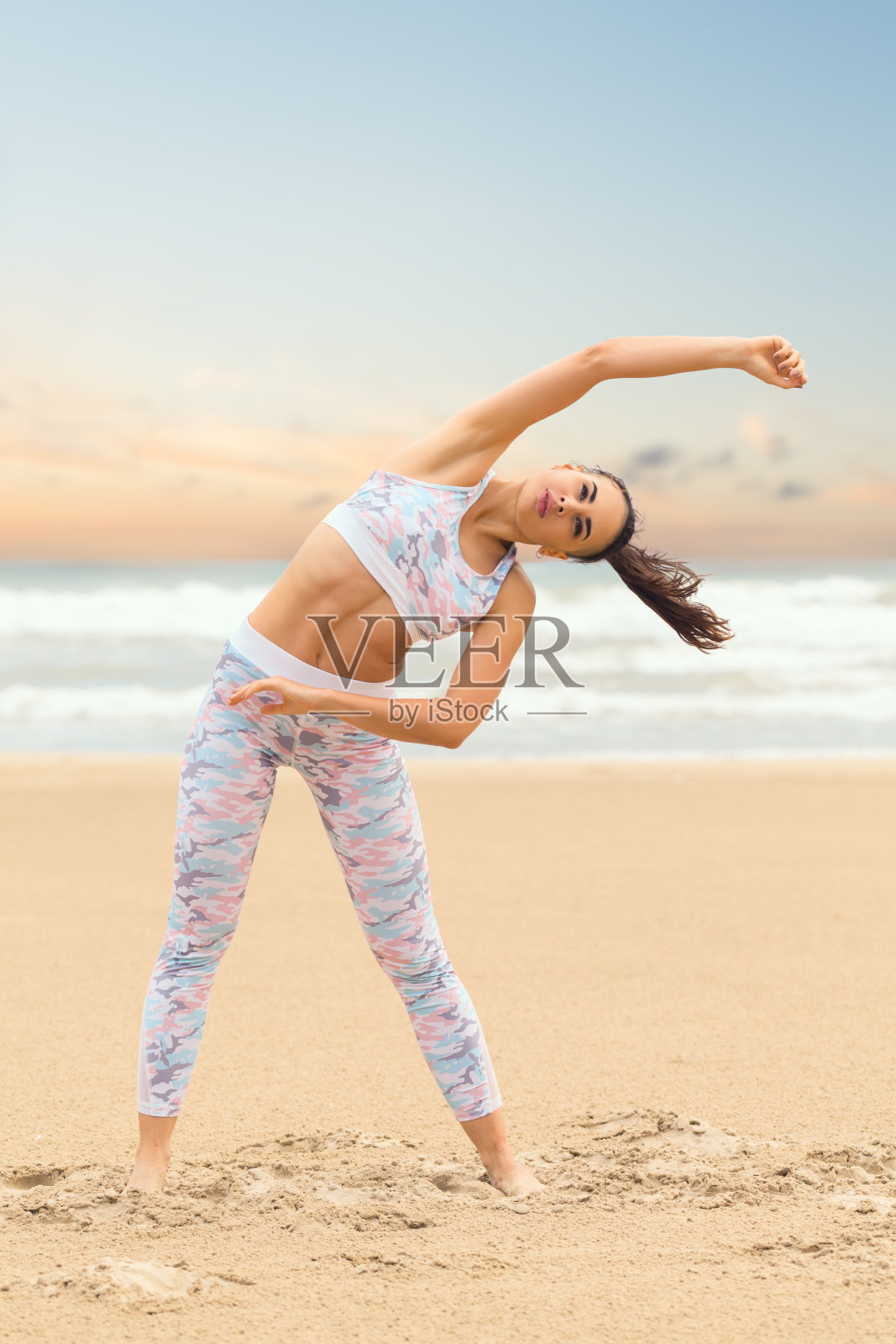 年轻美丽的女人在海沙上练习瑜伽照片摄影图片