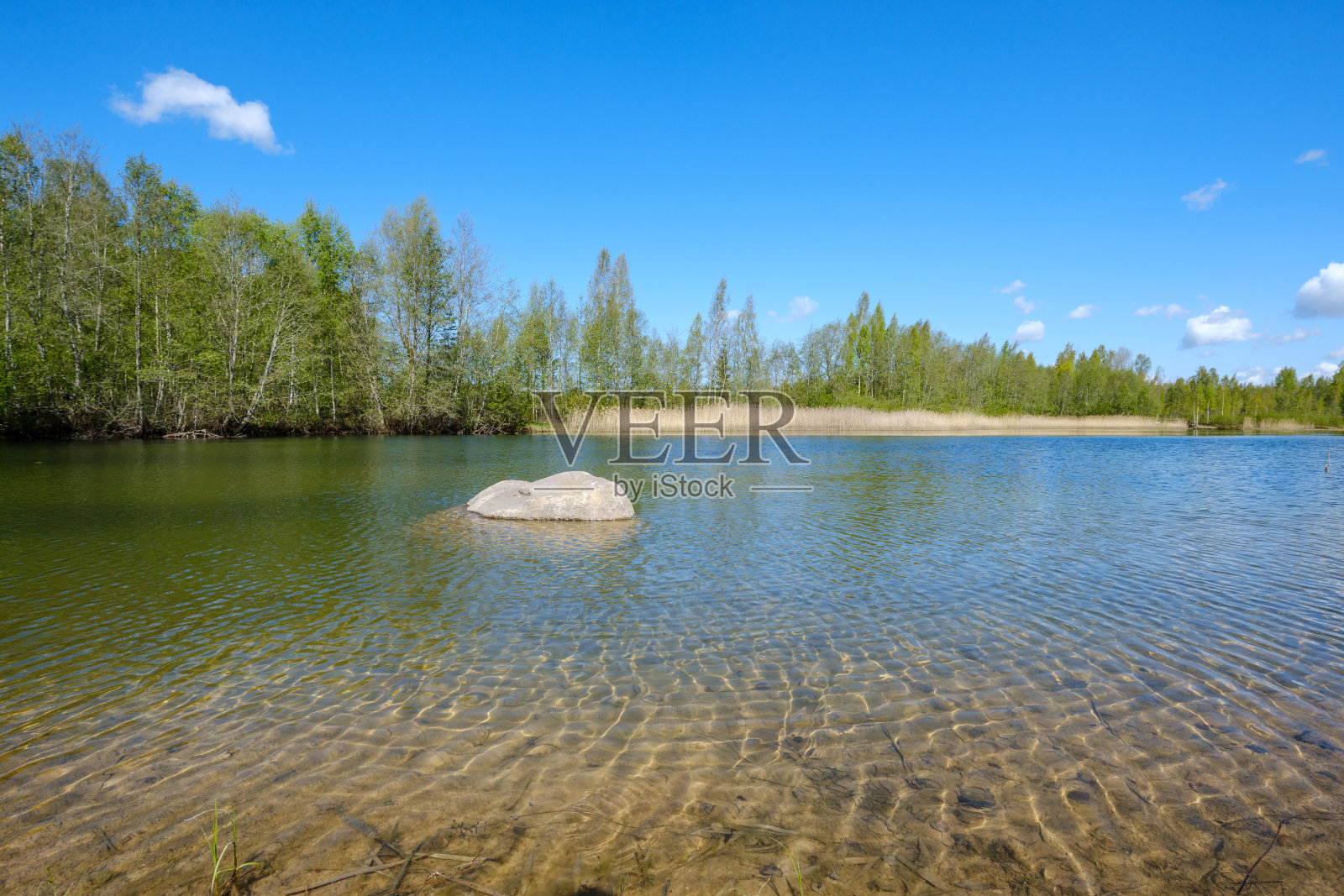 清澈透明的湖水,底部是沙,中间是大岩石照片摄影图片