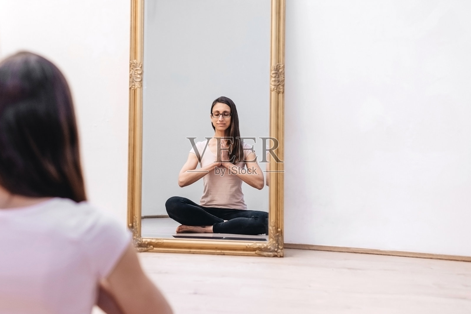 镜子映出一个正在练瑜伽的年轻女子照片摄影图片