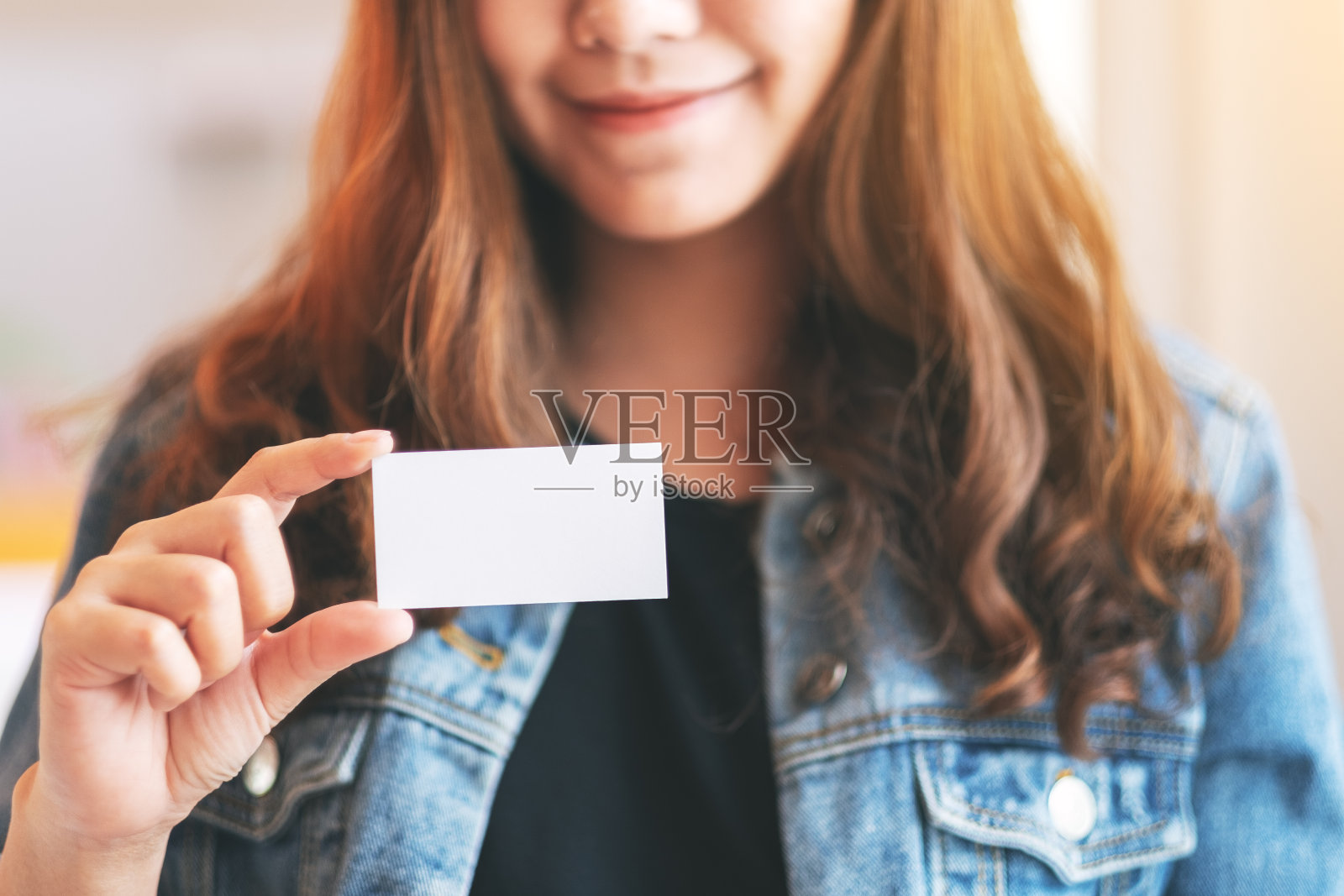 一个漂亮的女人拿着一张空白的名片给别人看照片摄影图片