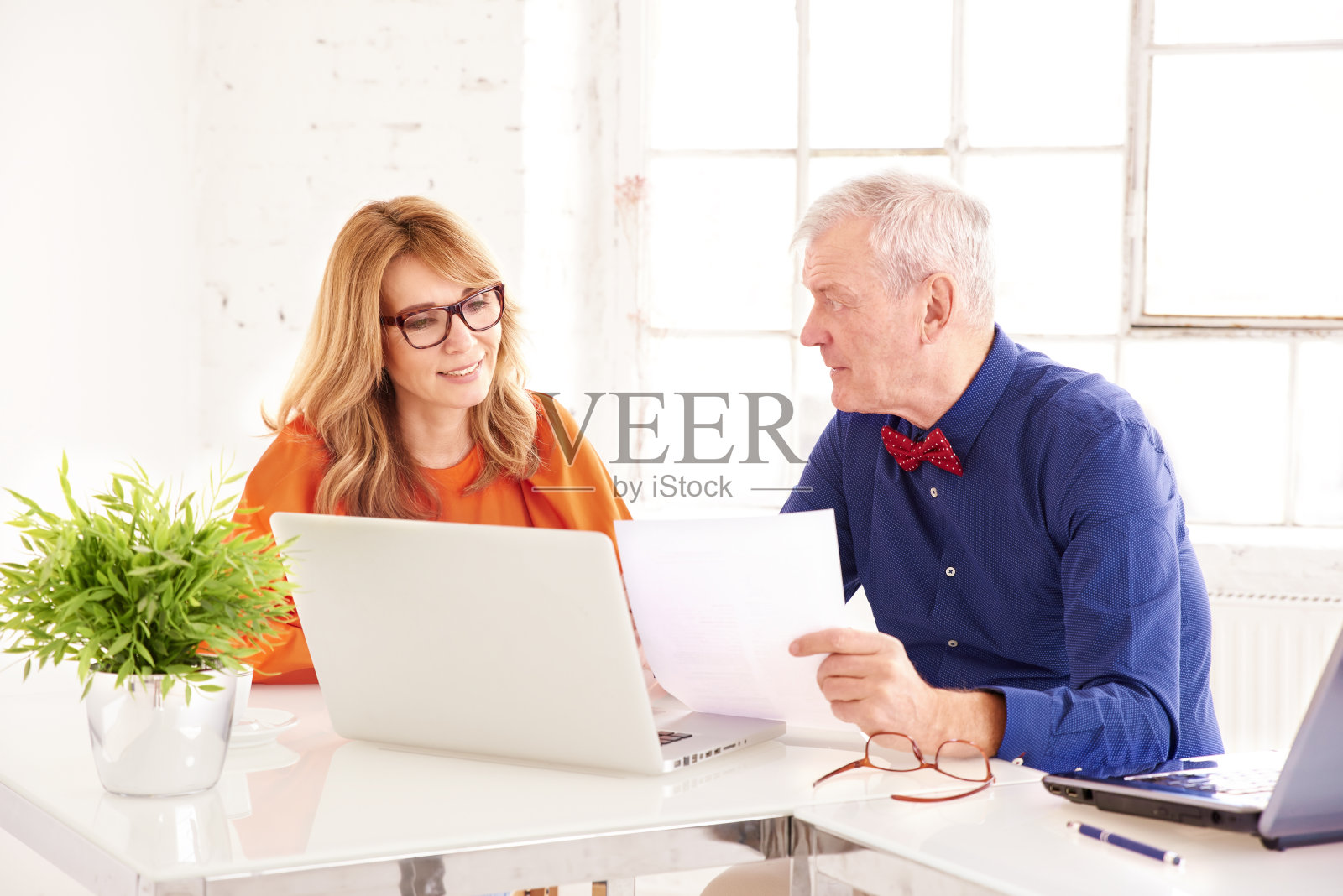 中年女商人和高级商人一起在办公室用笔记本电脑工作照片摄影图片