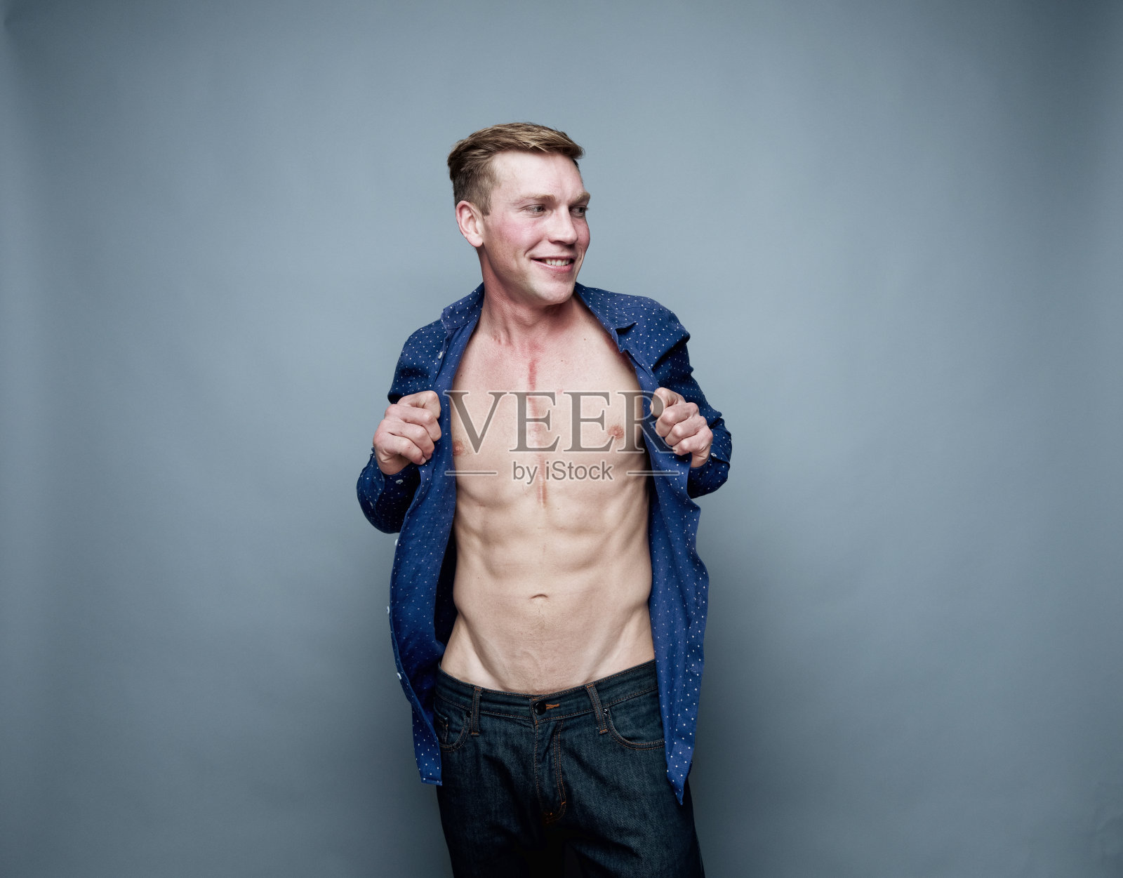 穿着蓝色衬衫,炫耀腹肌的帅哥照片摄影图片