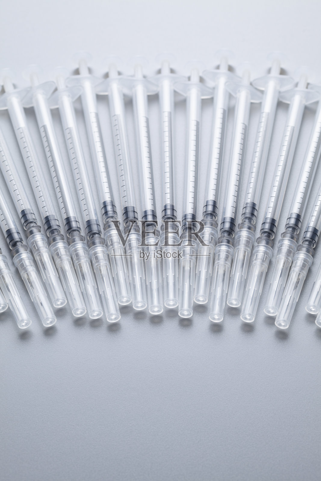 灰色桌子上放着带针的塑料注射器照片摄影图片