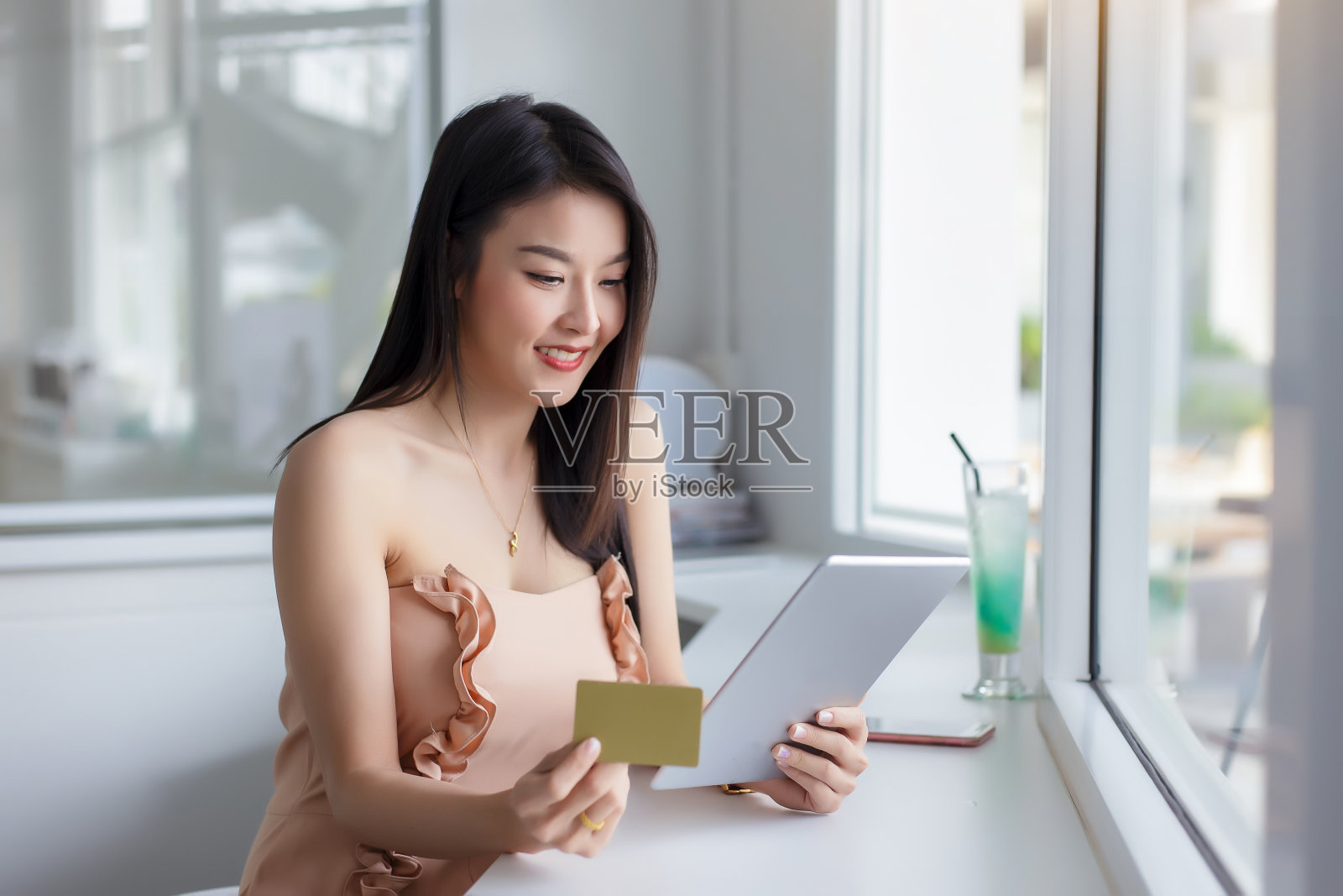 年轻的亚洲女性拿着信用卡,用着平板电脑。网上购物的概念。照片摄影图片