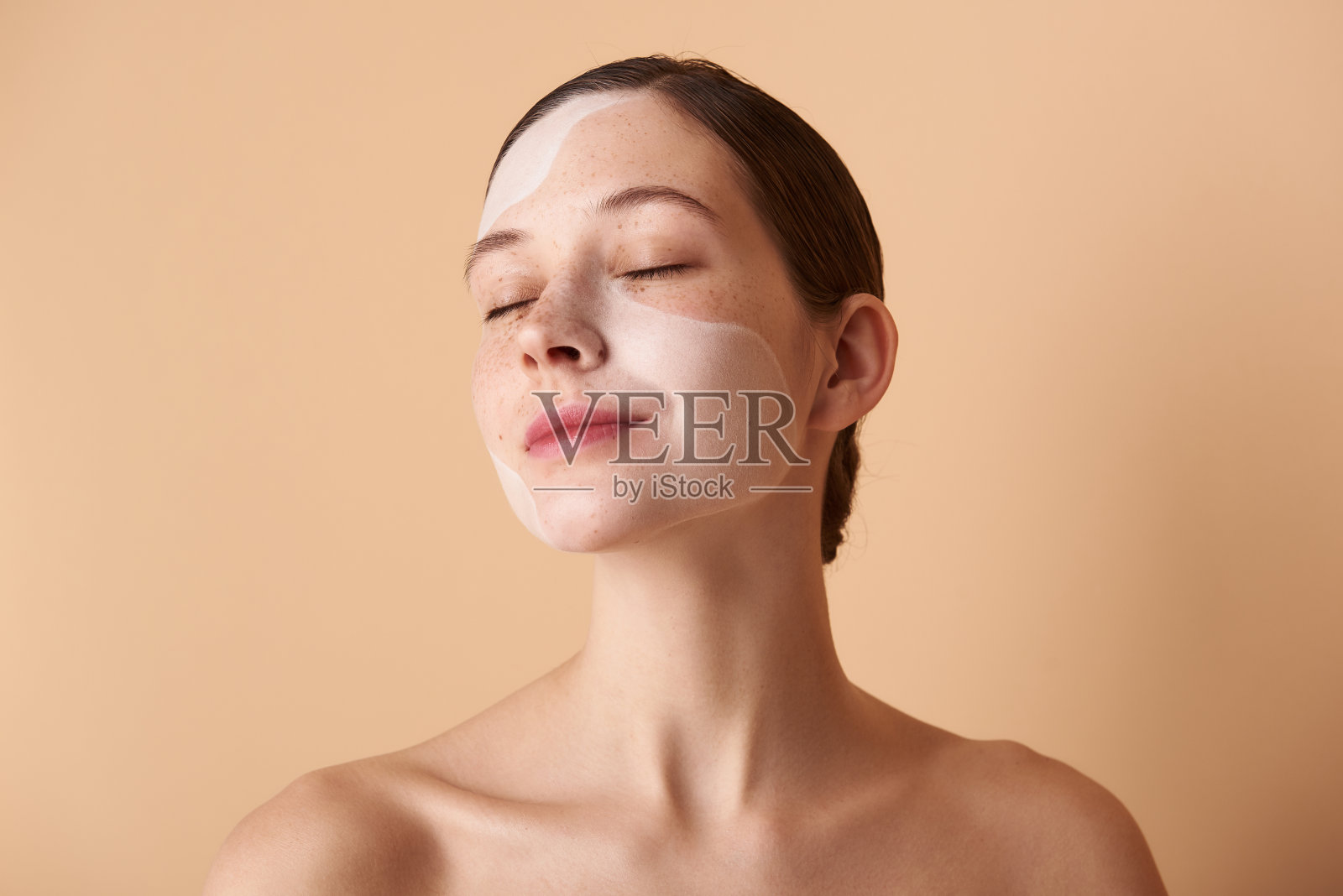 可爱放松的女孩,脸上带着面具,站在米色的背景下照片摄影图片