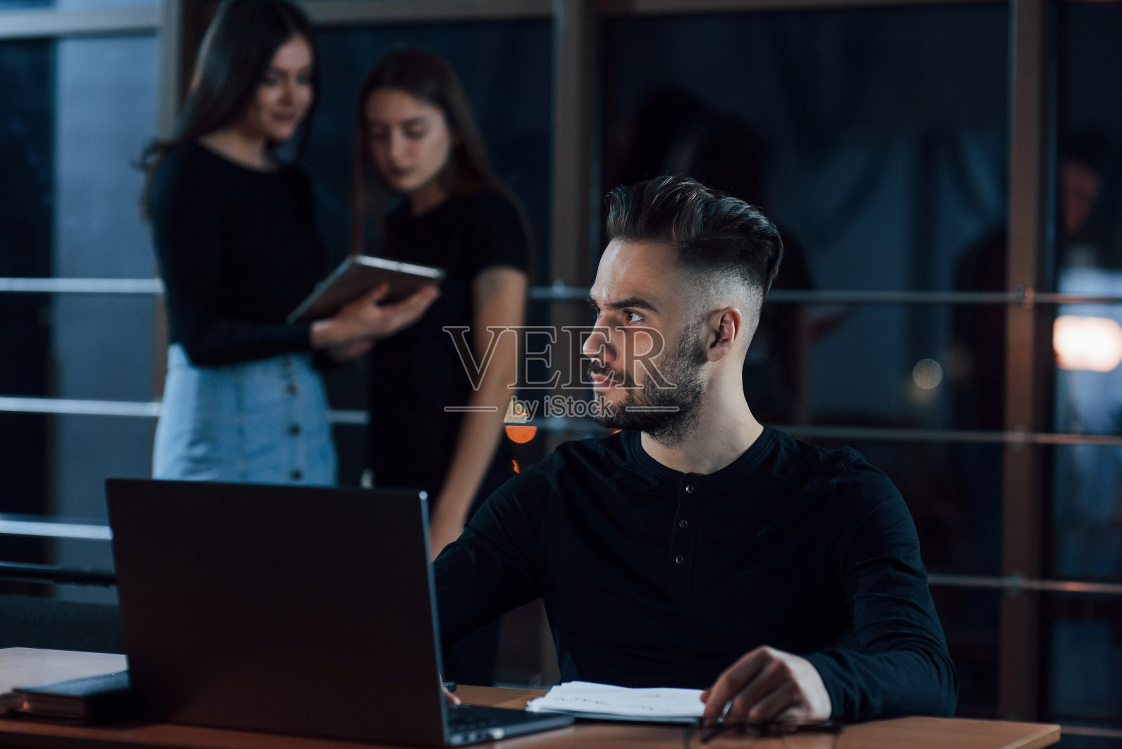 后面是女性员工。一群年轻的商人晚上在办公室里为他们的项目工作照片摄影图片