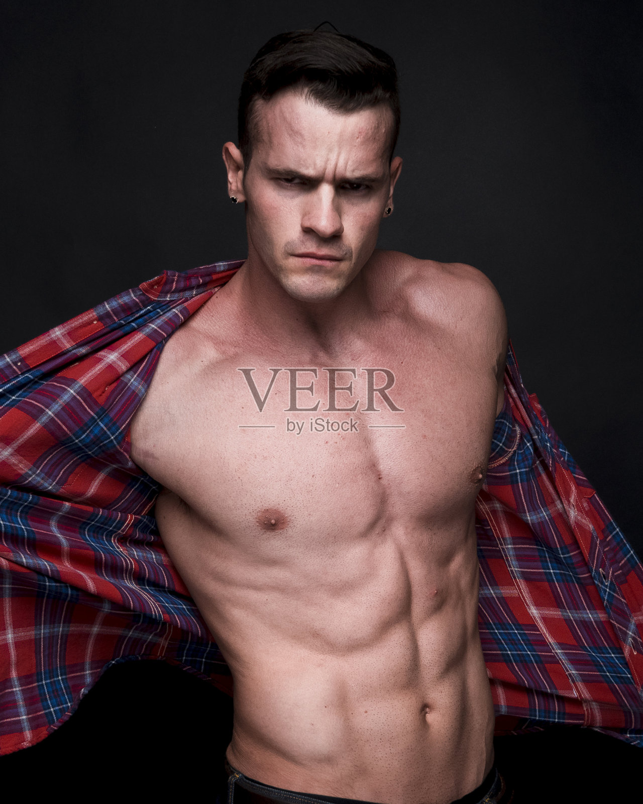 非常有吸引力的男子谁穿着一件解开的法兰绒衬衫和感觉性感照片摄影图片