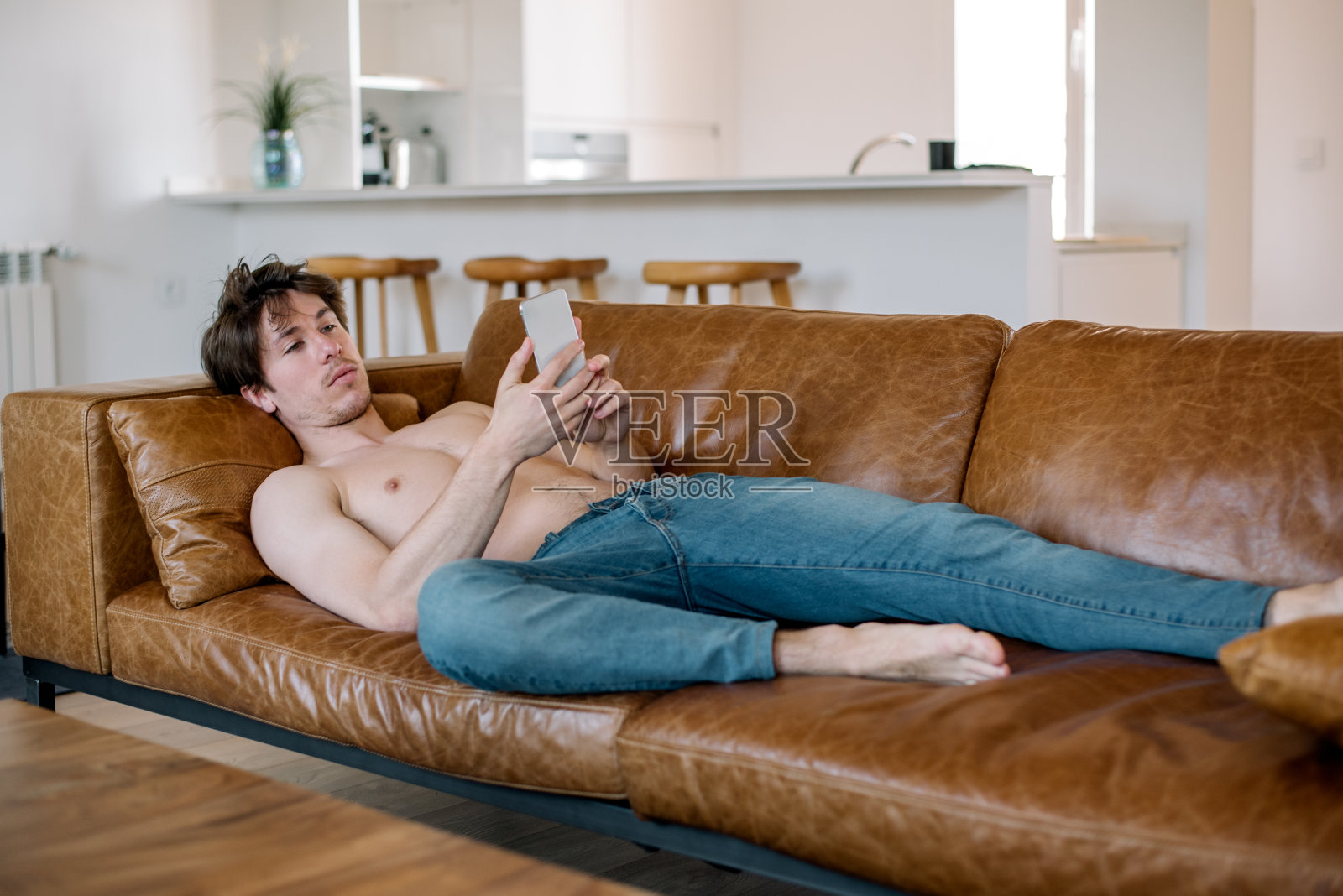 沙发上放着智能手机的快乐男人照片摄影图片