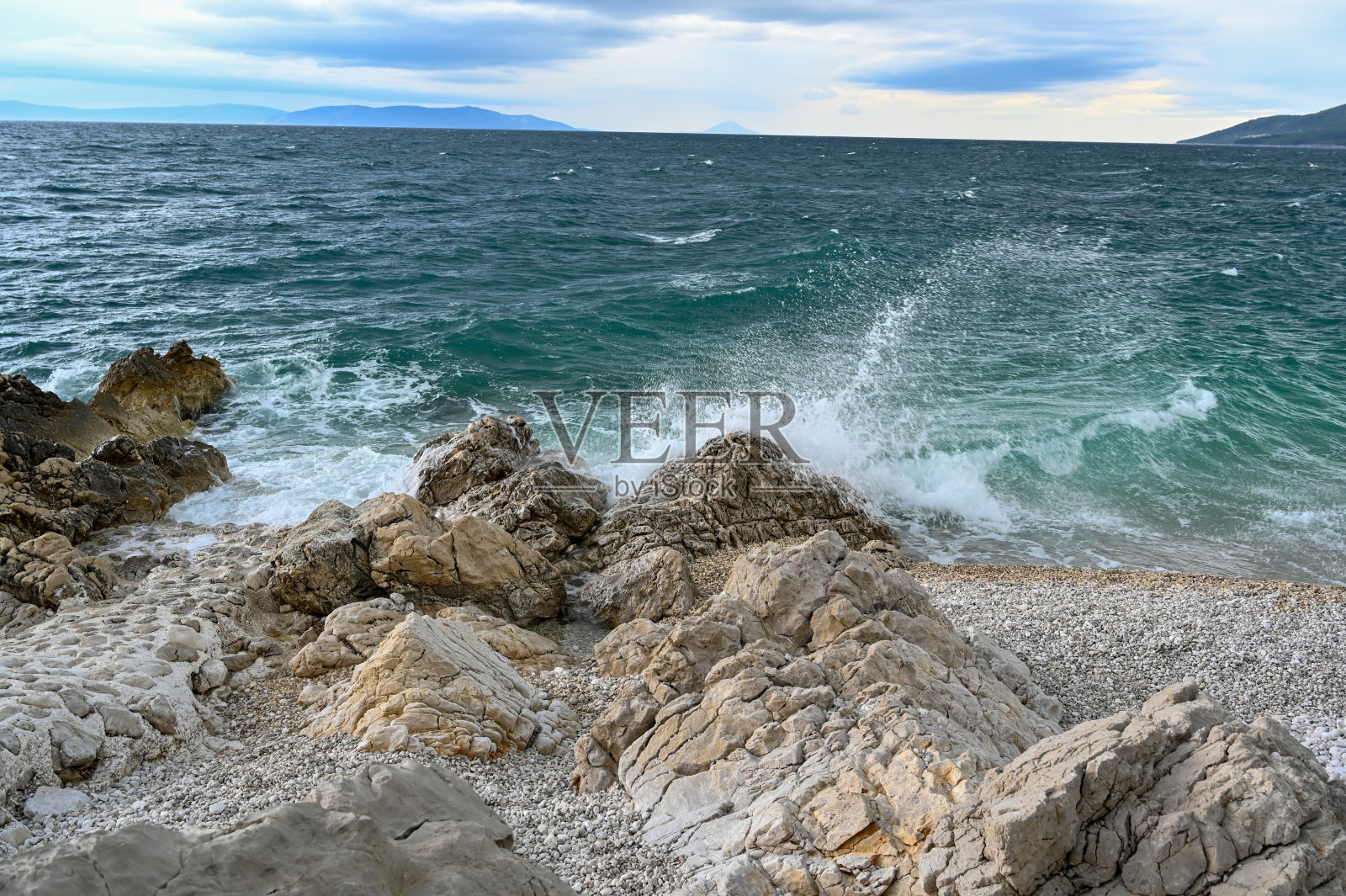 波浪在布满卵石的海滩上来来往往照片摄影图片