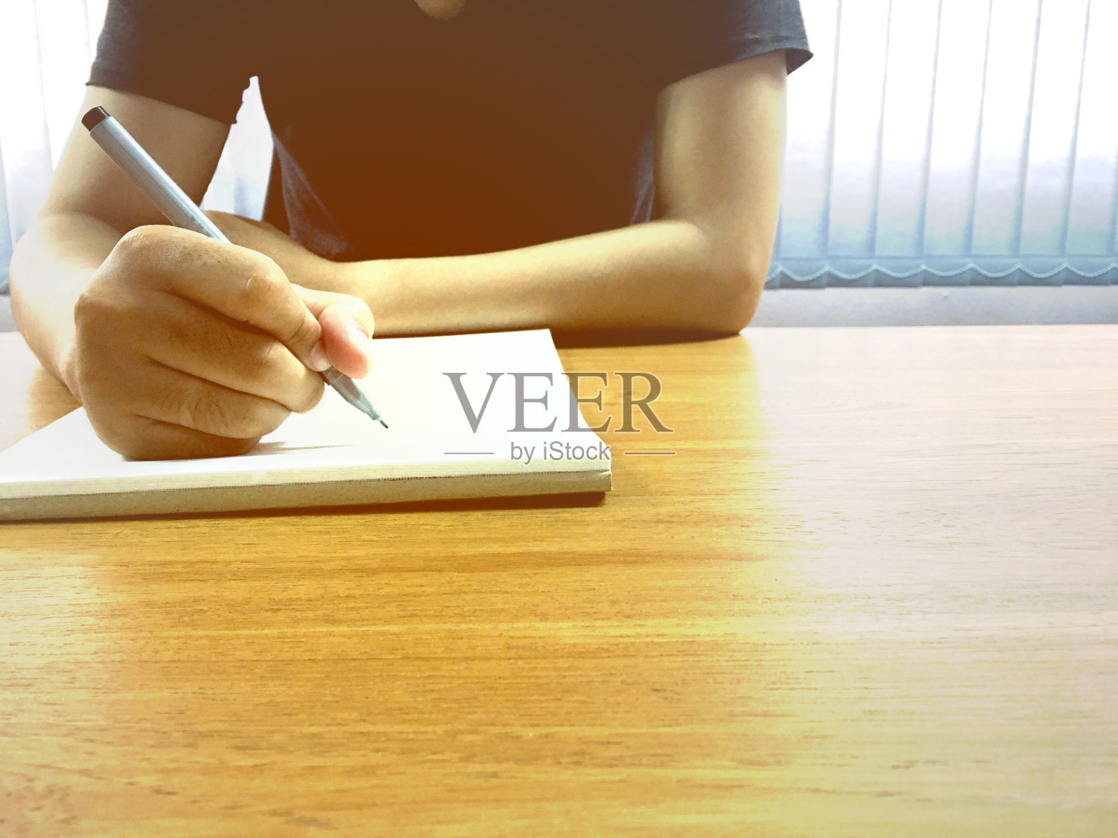 年轻的商人拿着笔在办公室的笔记本上手写。照片摄影图片