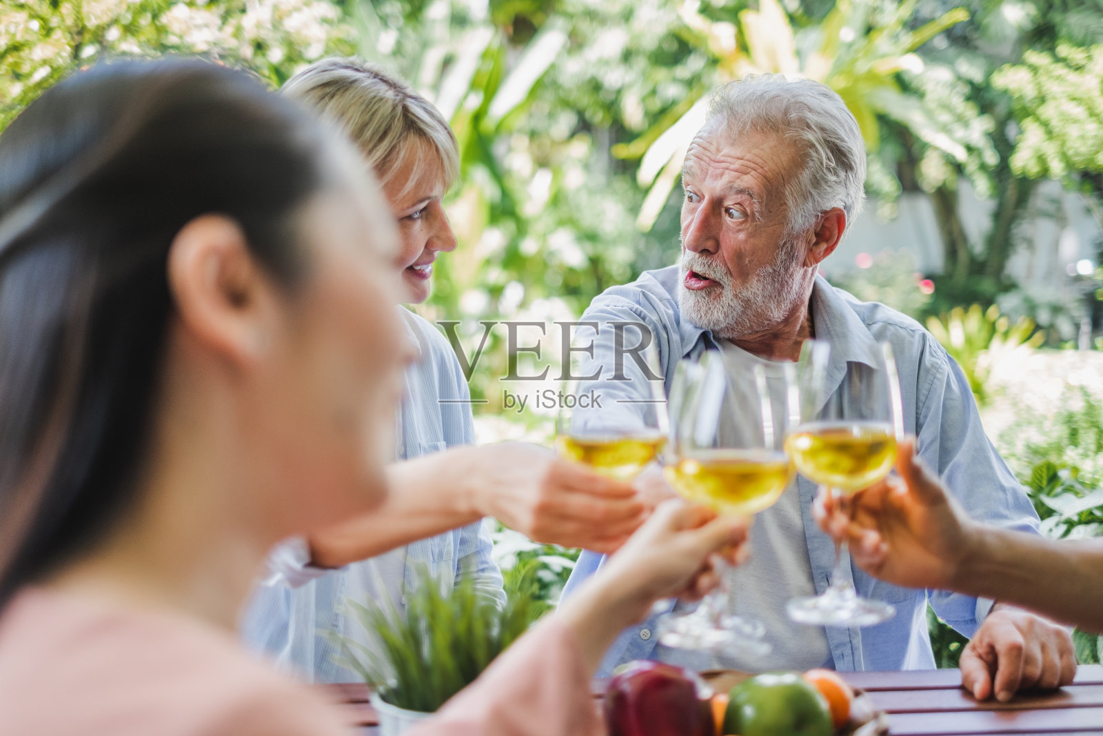 一群老年人在家享受聚会,喝着白葡萄酒,唱歌放松照片摄影图片