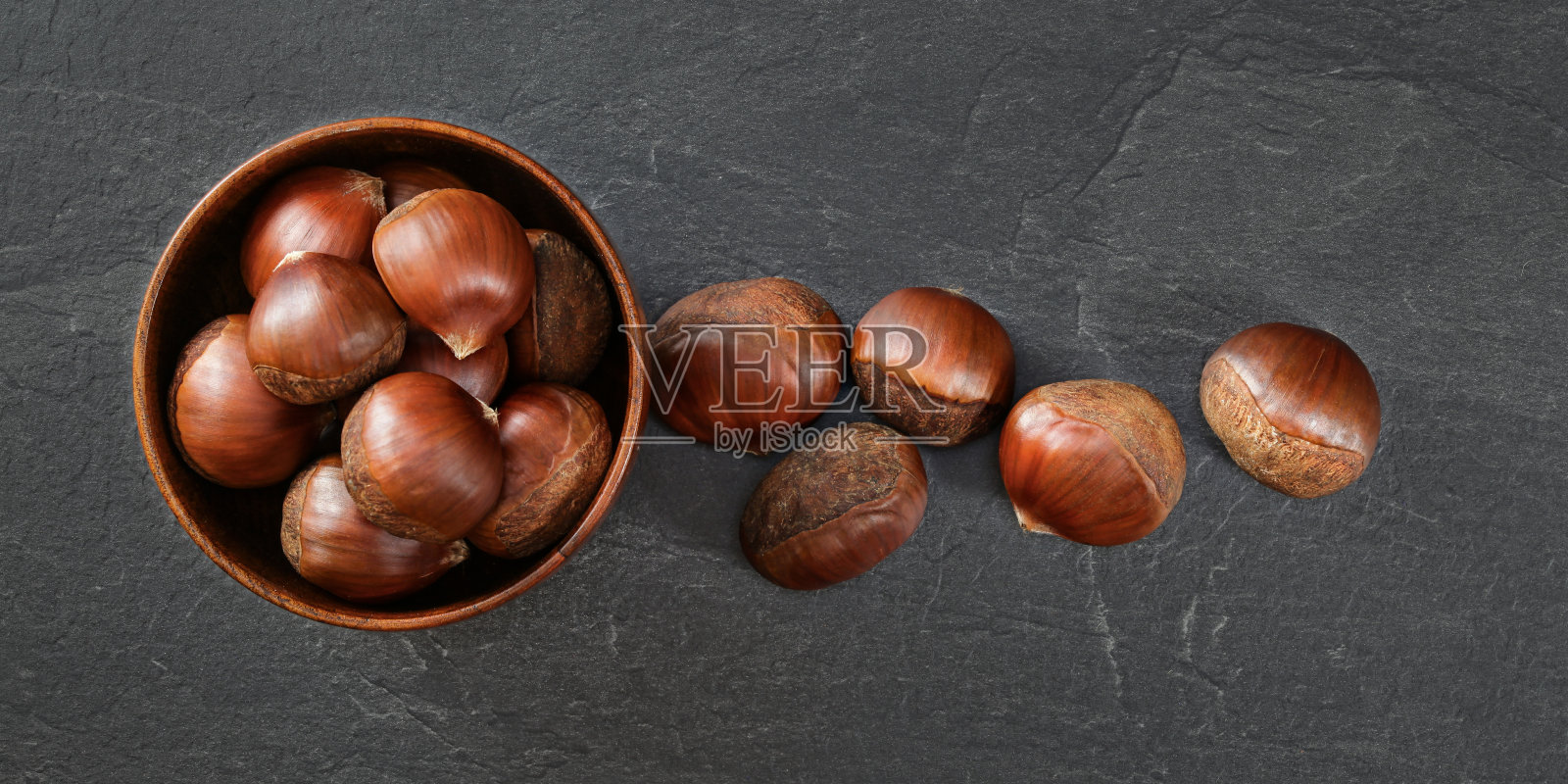 桌面照片-小木碗栗子,有些洒在石头上像工作板照片摄影图片