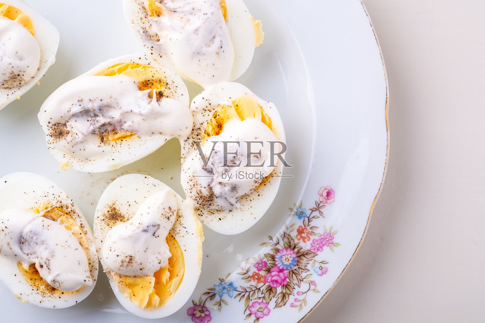 切片煮鸡蛋与蛋黄酱和胡椒在白色盘子孤立俯视图照片摄影图片