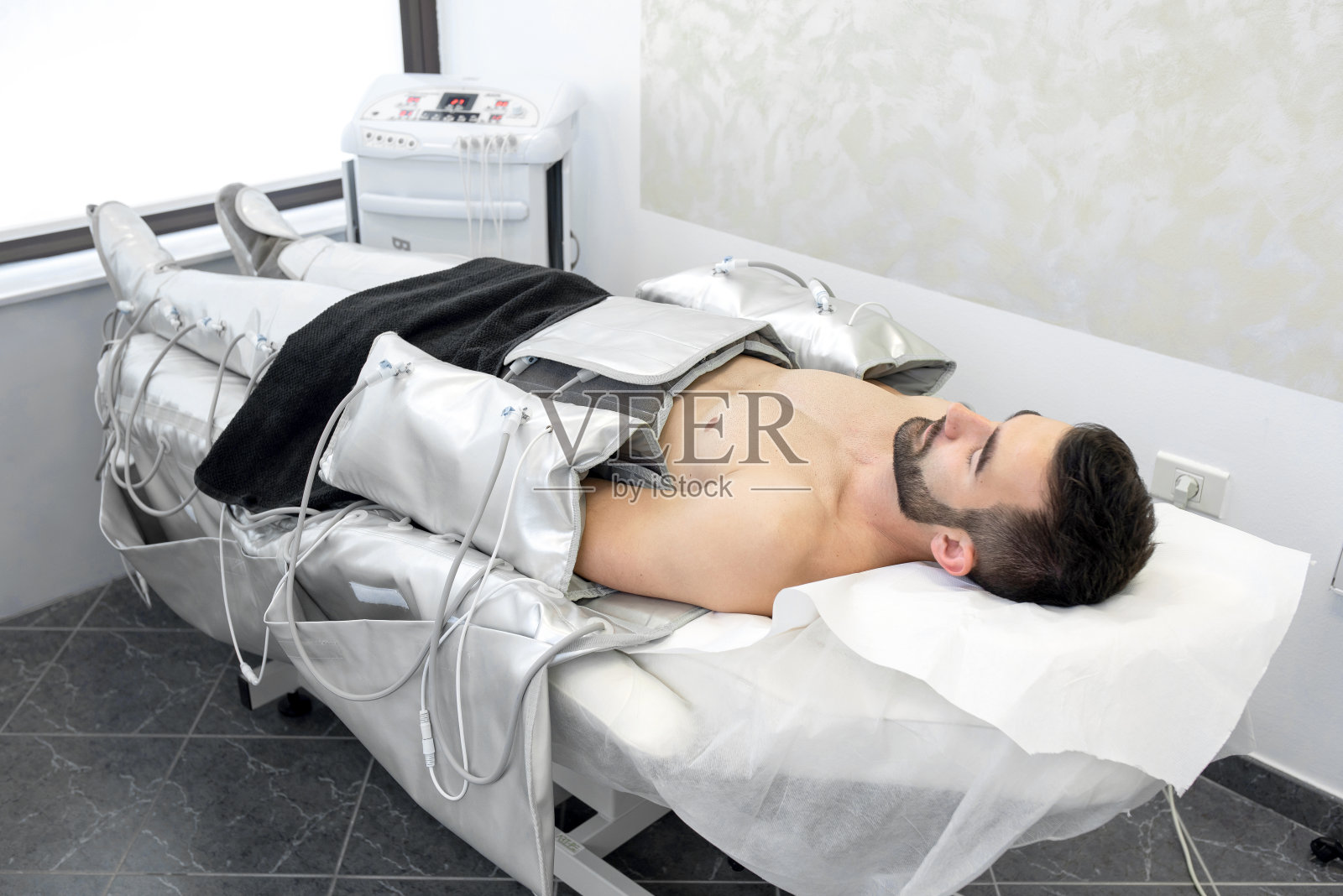 美容诊所里穿着压力疗法服躺着的男人照片摄影图片