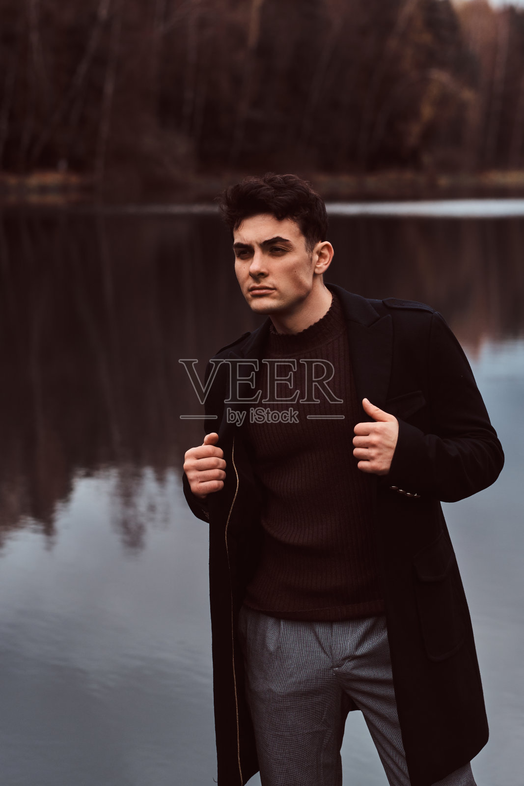 一个自信的年轻英俊的男人在秋天的森林里。照片摄影图片