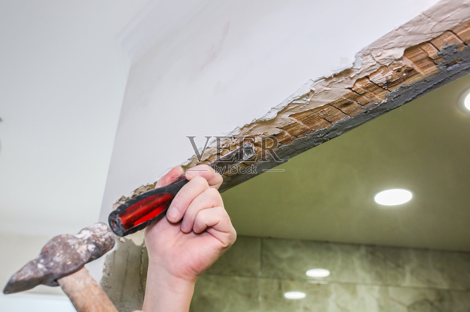 用手拿锤子凿。单位进行维修及翻新工程。恢复在室内。照片摄影图片