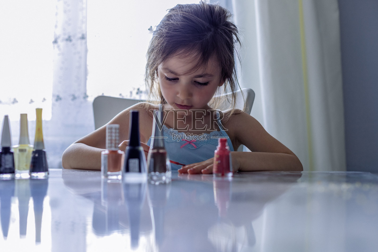 快乐的小女孩用她妈妈的指甲油照片摄影图片