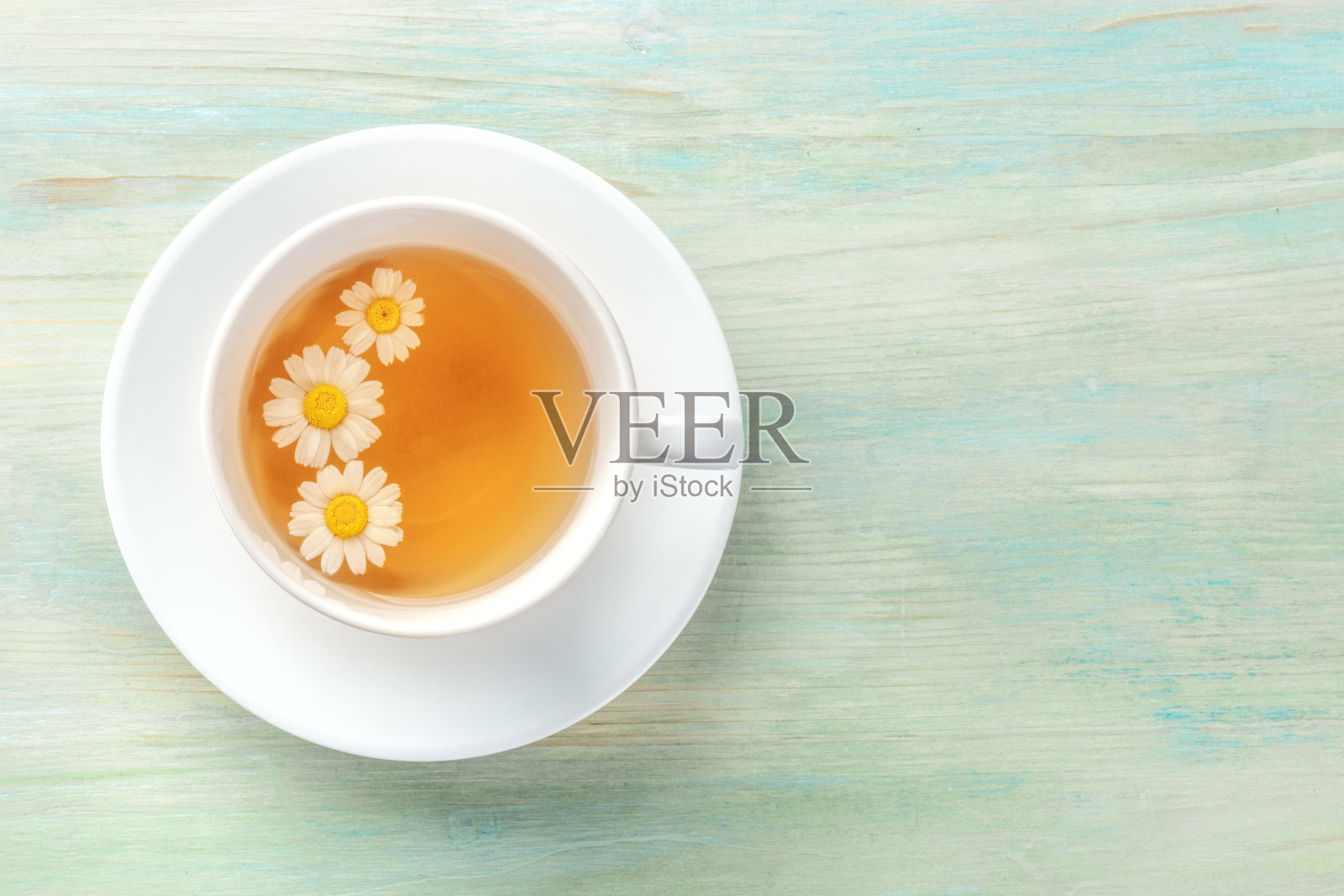 上面的照片一杯甘菊茶在蓝绿色的背景与copyspace照片摄影图片