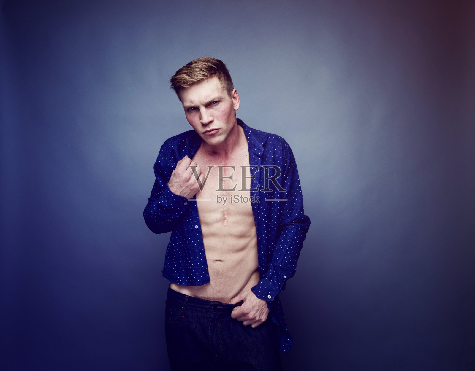 穿着蓝色衬衫,炫耀腹肌的帅哥照片摄影图片