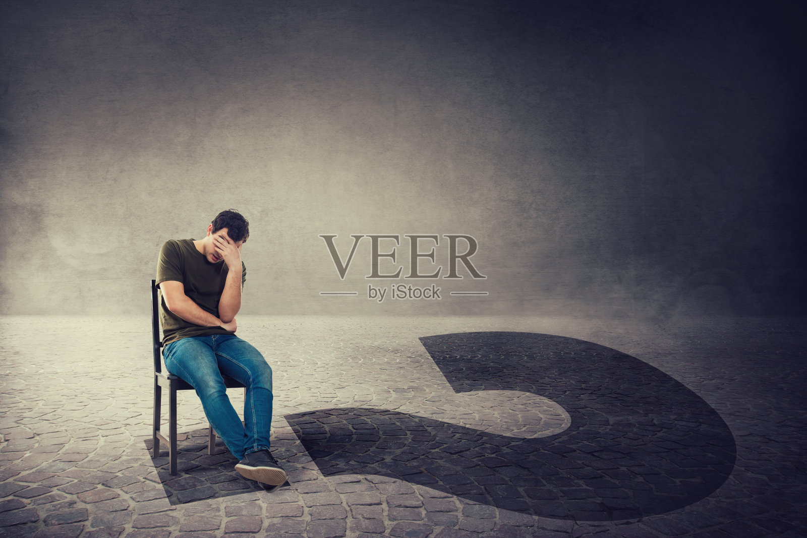 决策和人生的问题如同一个深思熟虑的焦虑者,坐在黑暗房间的椅子上,手扶着额头投下巨大的问号阴影照片摄影图片