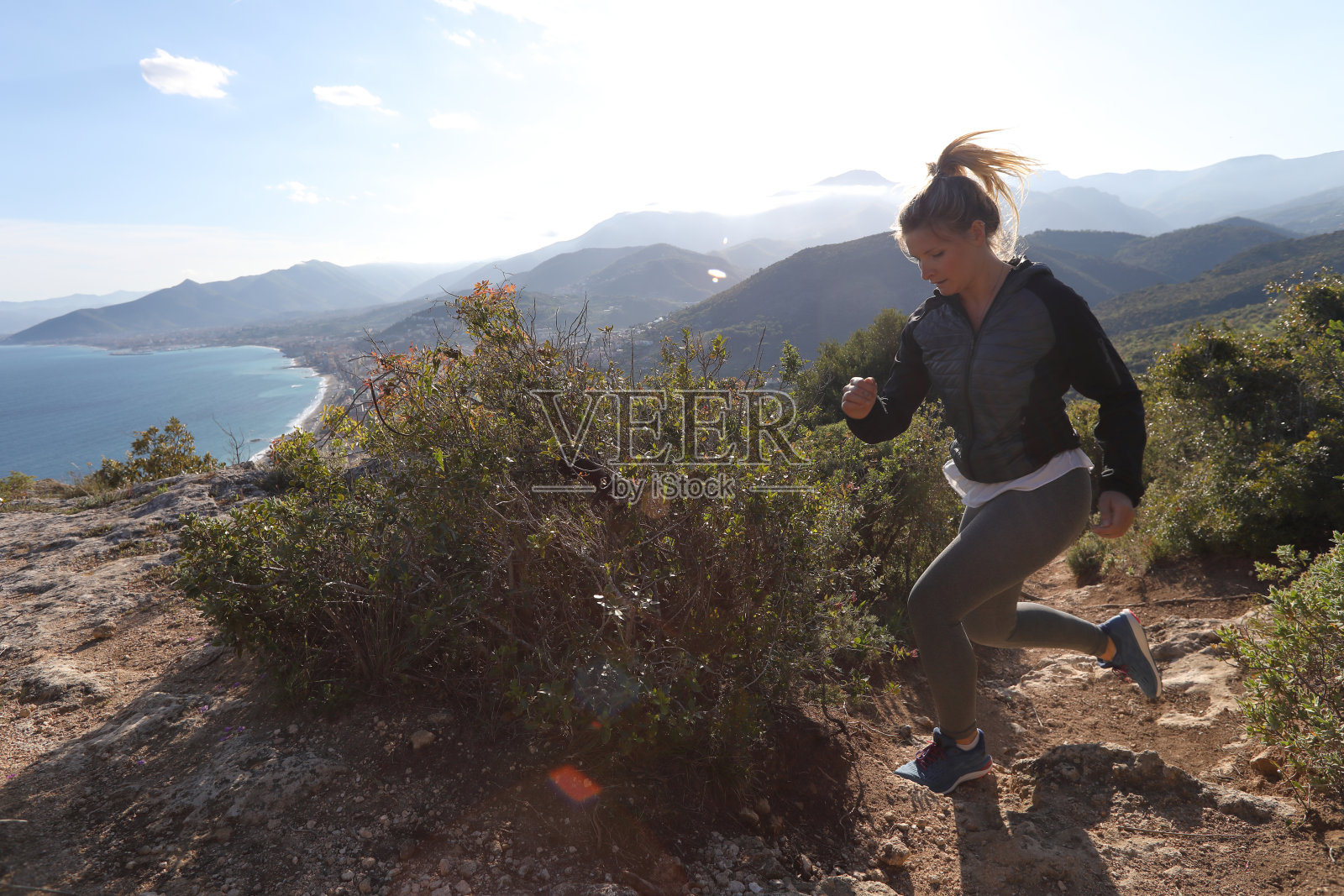 年轻的女人跑上了海边的山丘照片摄影图片