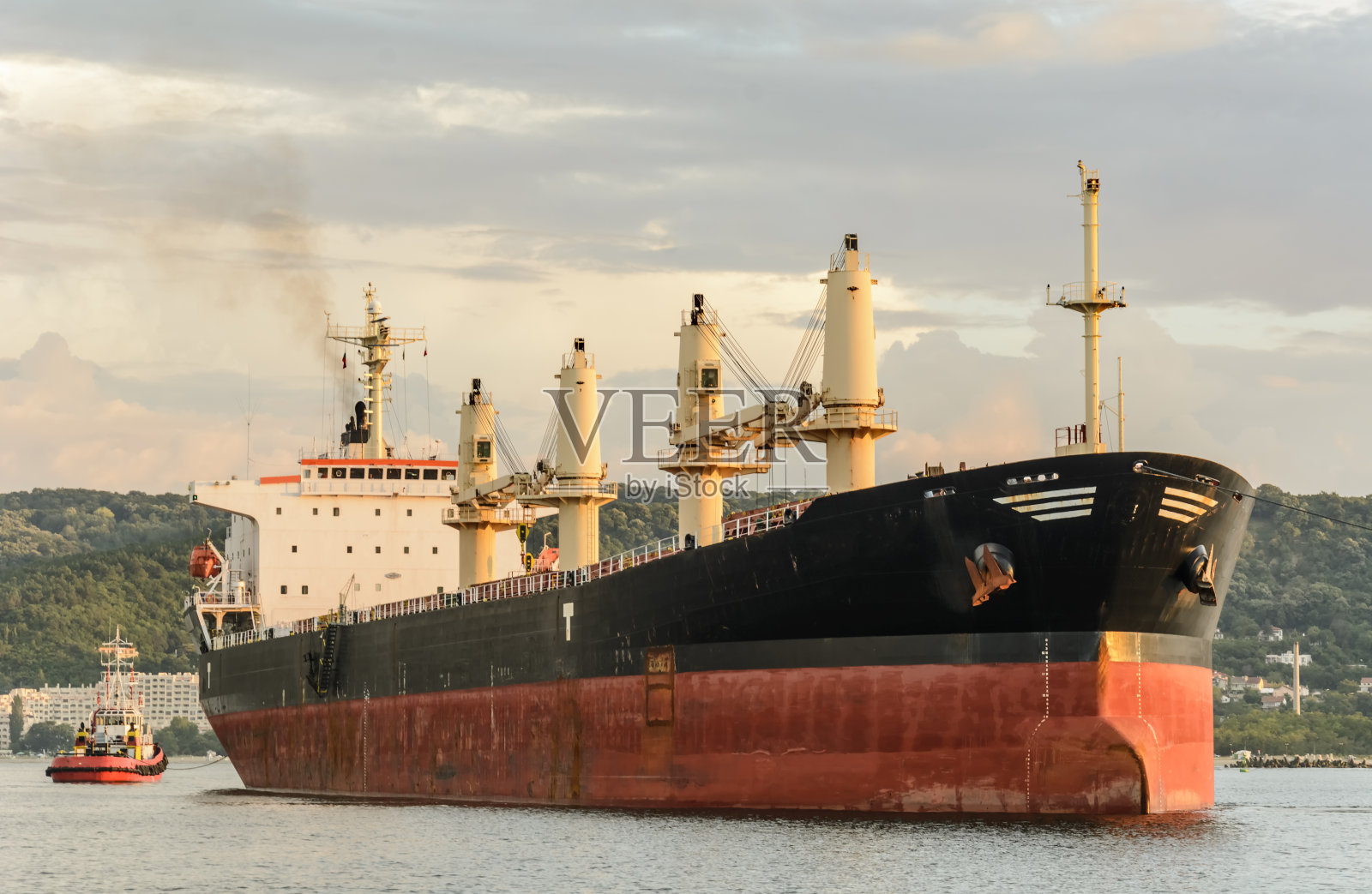 拖船载着大型货轮进港。照片摄影图片