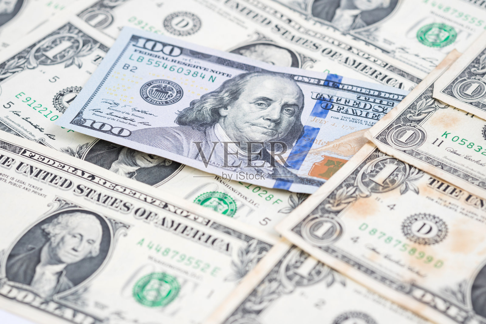 一百元钞票堆在一堆一元钞票里。照片摄影图片