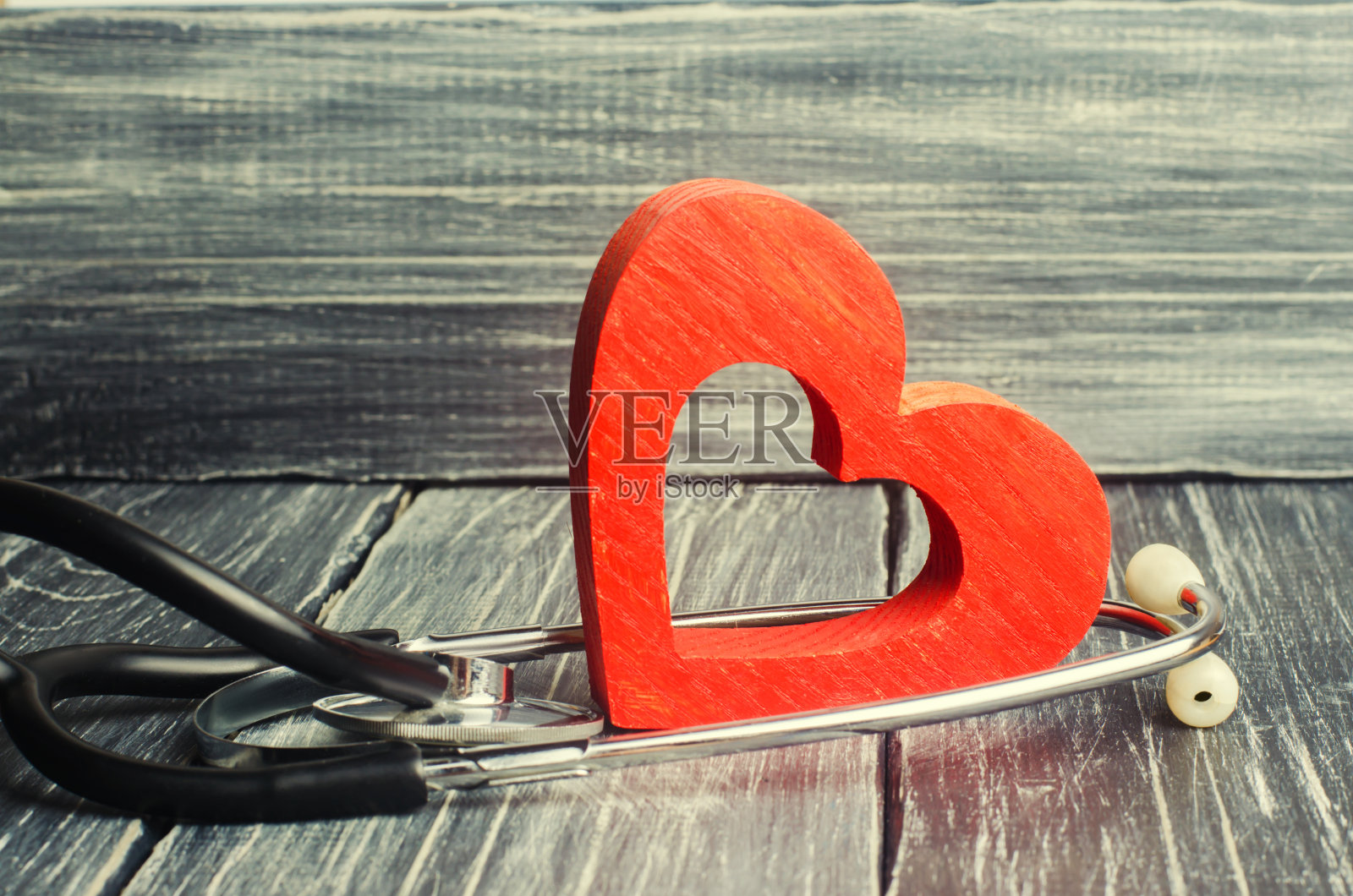 家庭医疗和保险的概念。木质背景上的听诊器和心脏照片摄影图片