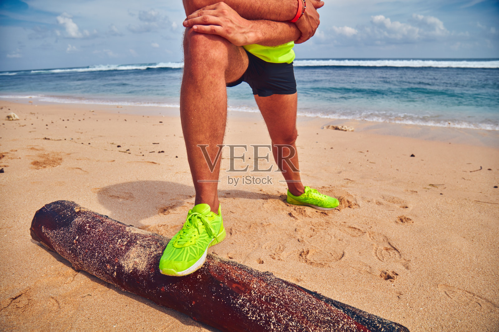 运动员在热带沙滩上伸展身体。照片摄影图片