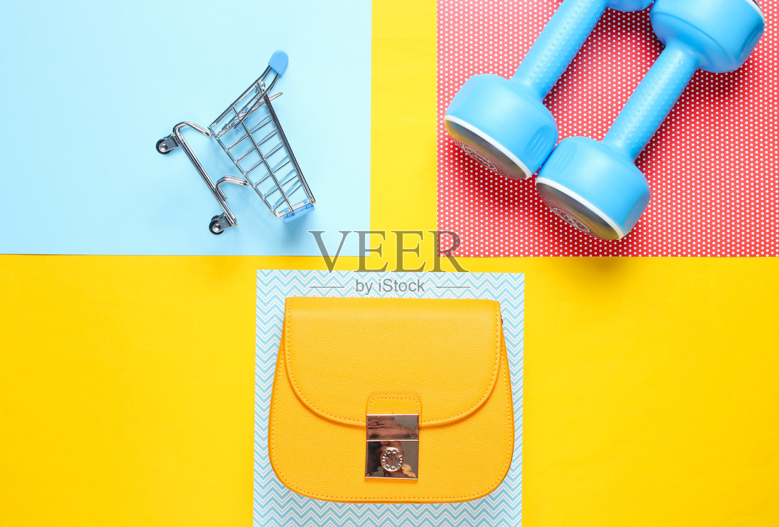 买家,购物狂的概念。袋子,迷你购物车,运动哑铃在创意的背景。极简主义。前视图。平躺照片摄影图片