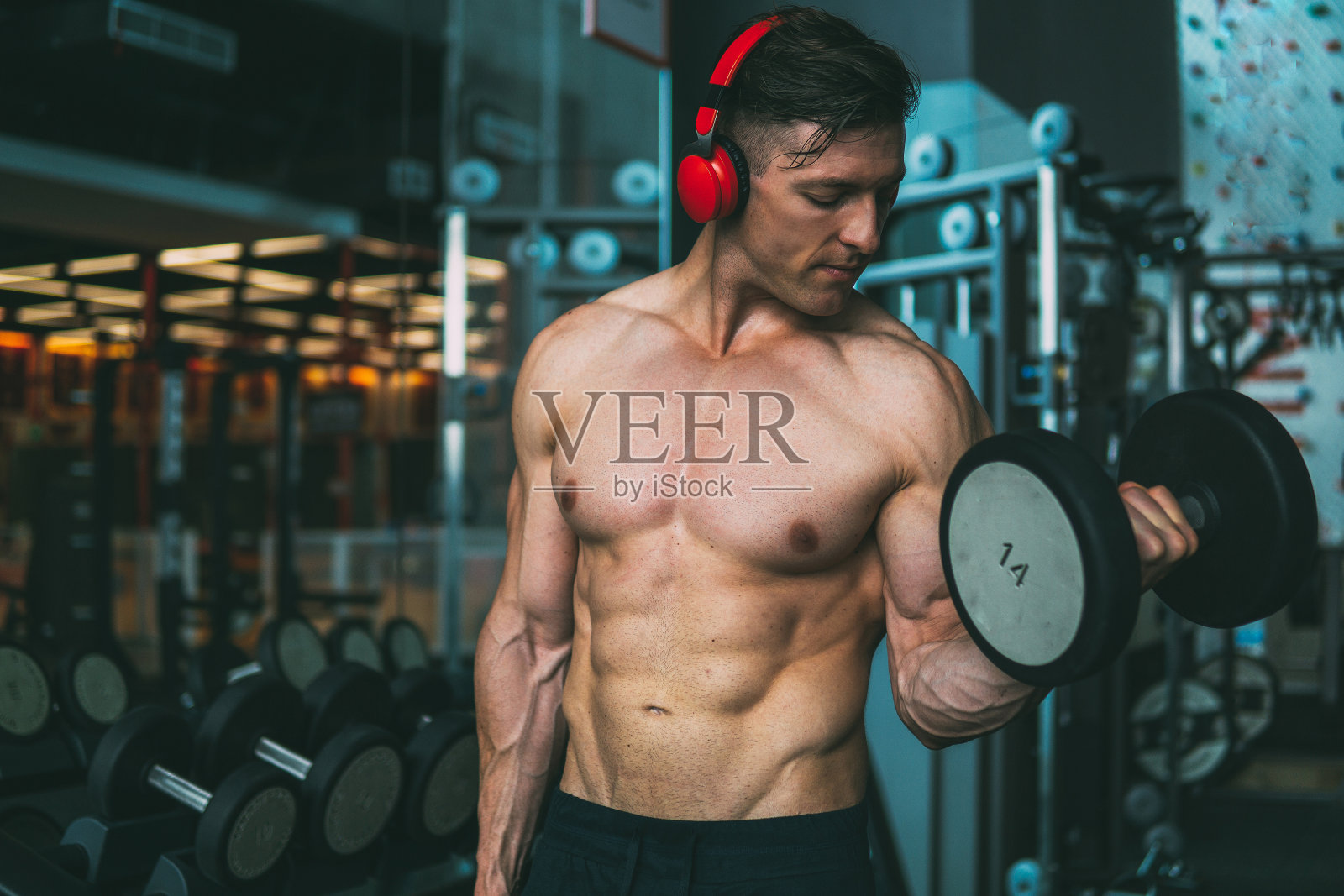 肌肉男在健身房练哑铃照片摄影图片