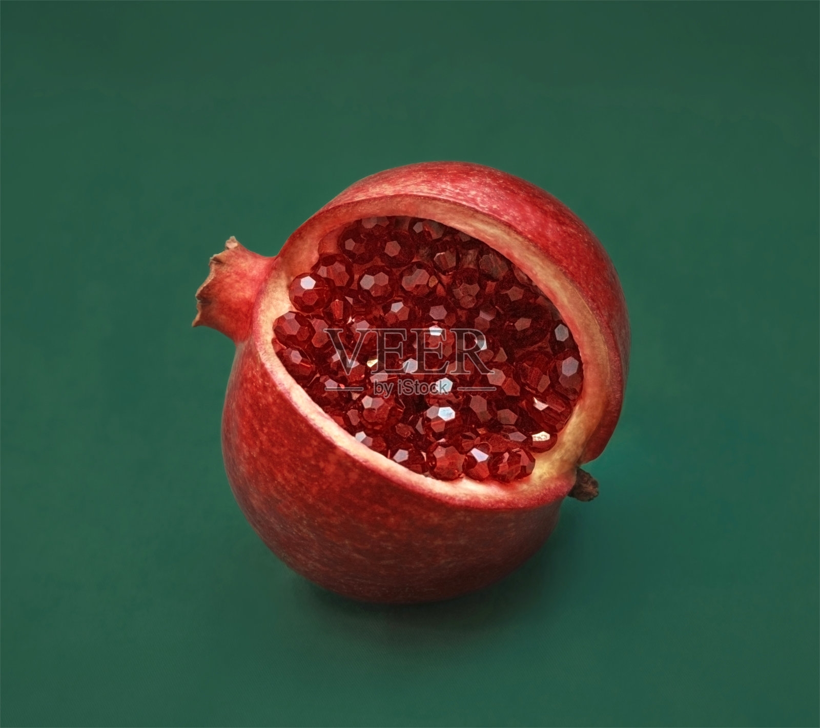美丽的红石榴切片在绿色的背景。石榴果实有红色发亮的珠子,石榴石晶体代替种子和谷粒。宏观,近距离,抽象。珠宝不寻常的水果。照片摄影图片