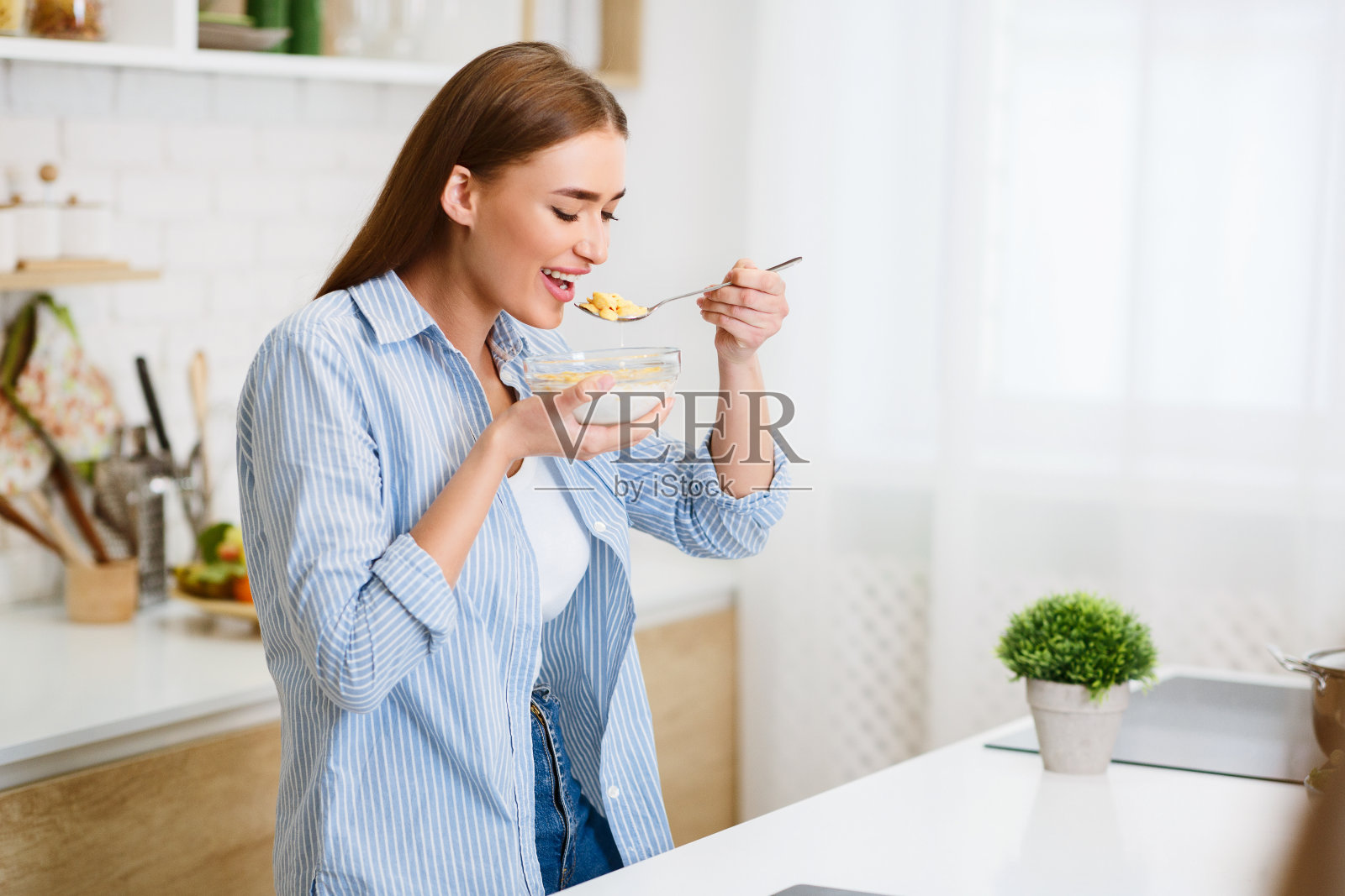 在厨房里吃玉米片的女人照片摄影图片