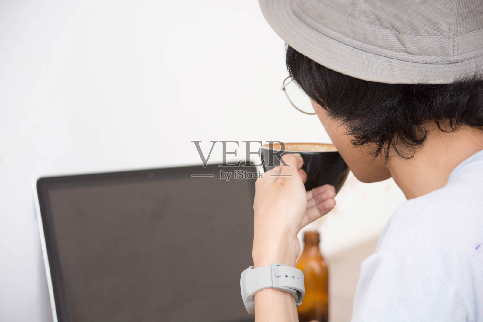 后视图。年轻有创意的人在白衬衫和帕多拉帽坐在桌子上照片摄影图片