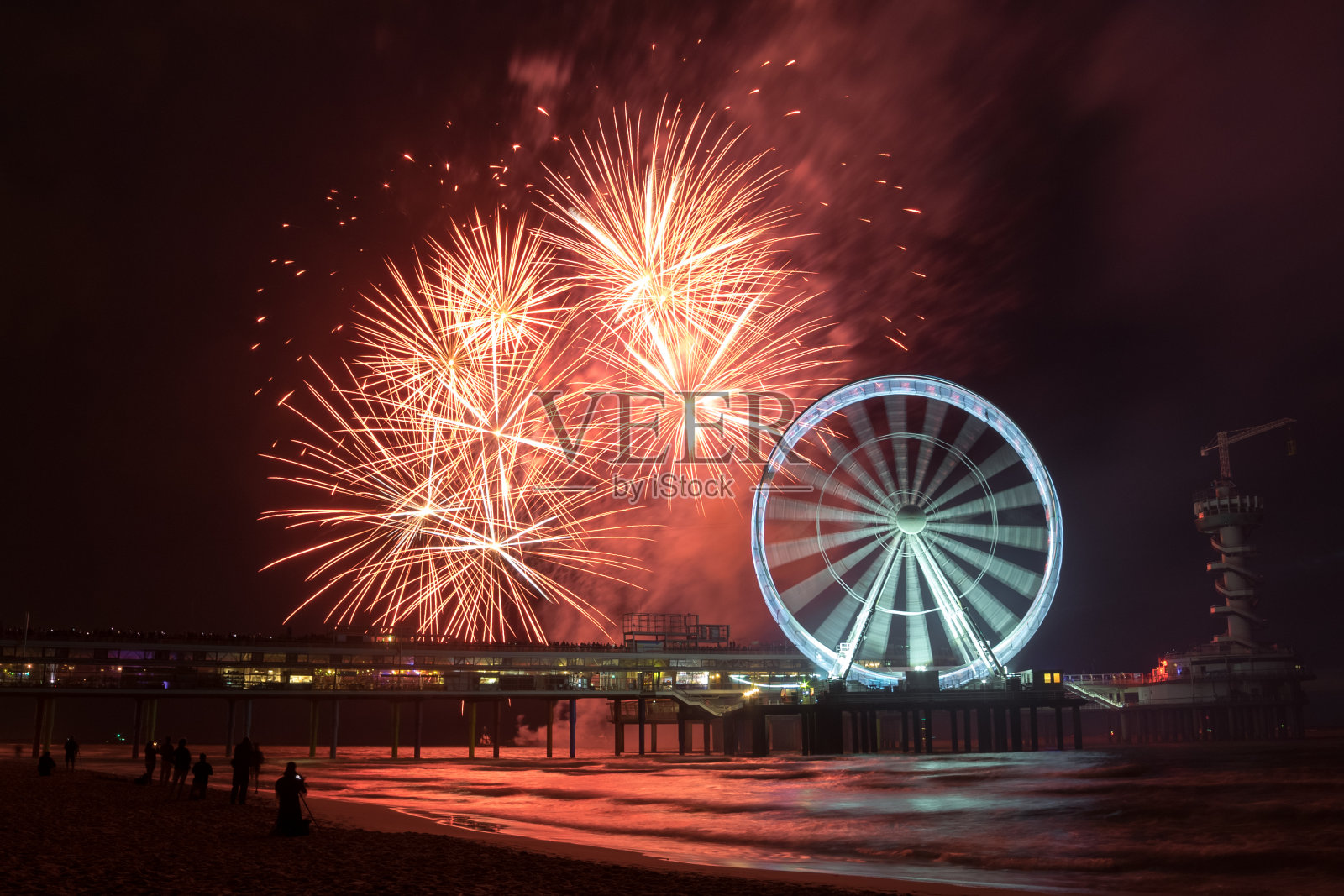 在荷兰海牙附近的斯赫弗宁根码头,旋转的摩天轮上放着烟花。照片摄影图片