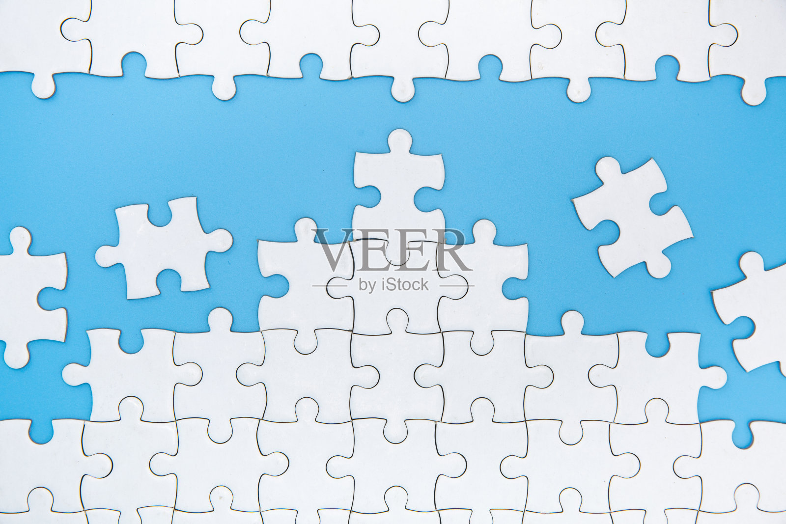 蓝色背景上未完成的白色拼图,拼图的最后一块,复制空间。照片摄影图片
